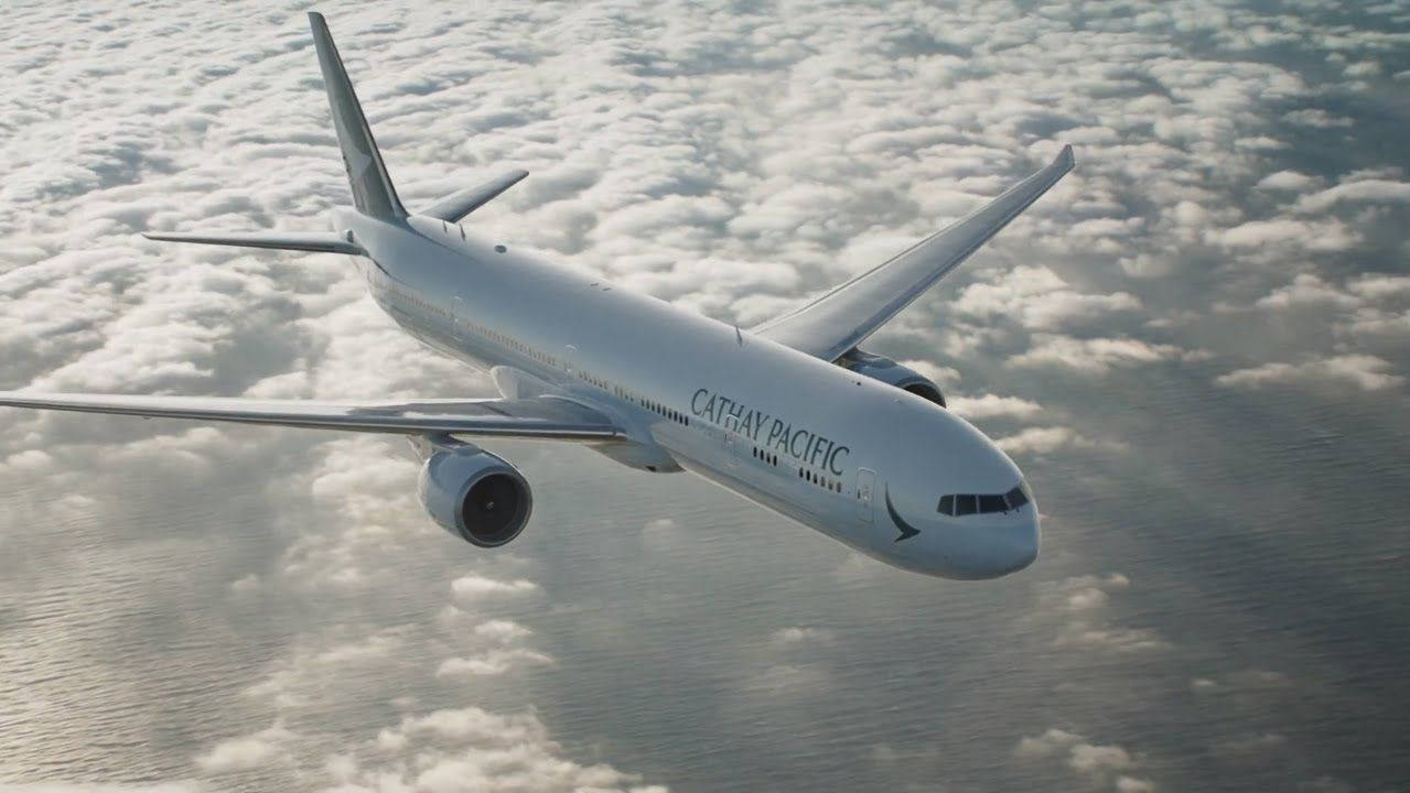 國泰航空飛機在白天飛越雲層和海洋。