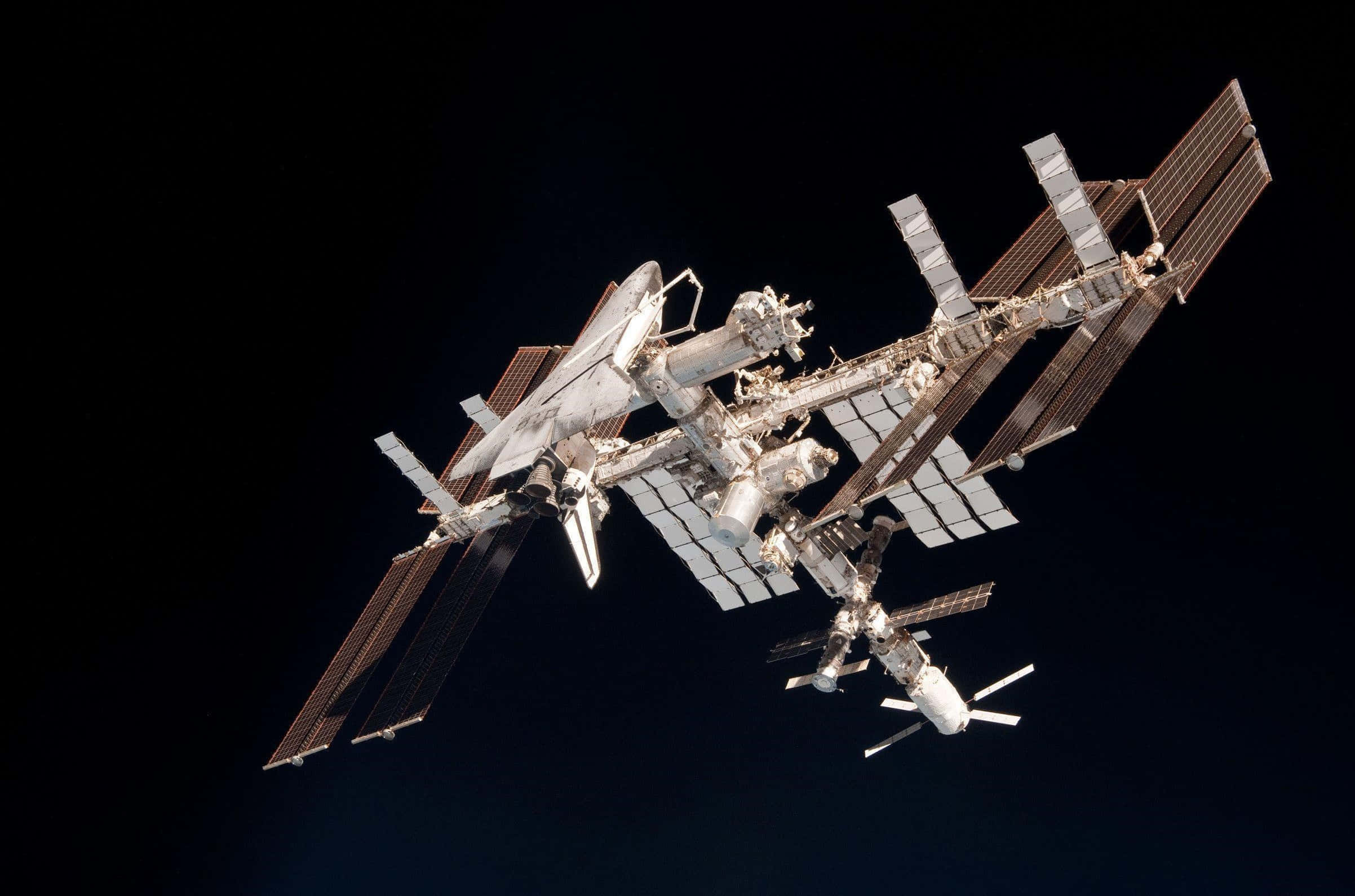 Iss 桌布 壁紙 — 國際太空站喺深邃太空嘅漆黑背景下，閃耀住複雜嘅金屬細節。