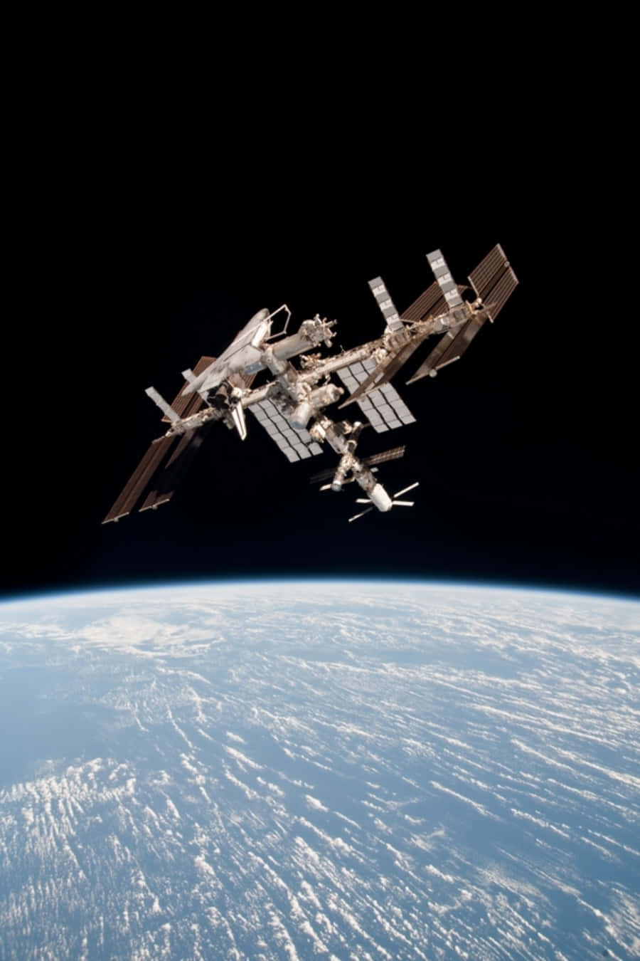 國際太空站於地球軌道上的壯麗景象 壁紙 — 一個詳細的太空站繞地球運行，太陽能板在藍色星球上方的黑色虛空中展開。