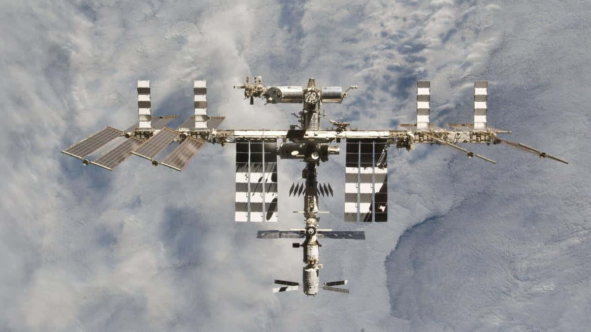 International Space Station 桌布 壁紙 — 國際太空站漂浮在地球旋轉的雲層和藍色海洋之上，呈現出令人嘆為觀止的軌道景觀。