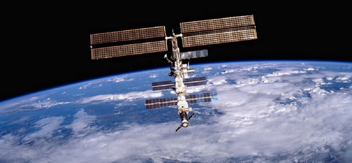 International Space Station 桌布 壁紙 — 國際太空站繞地球運行，顯示藍色海洋、白色雲層和黑色太空中的彎曲地平線。