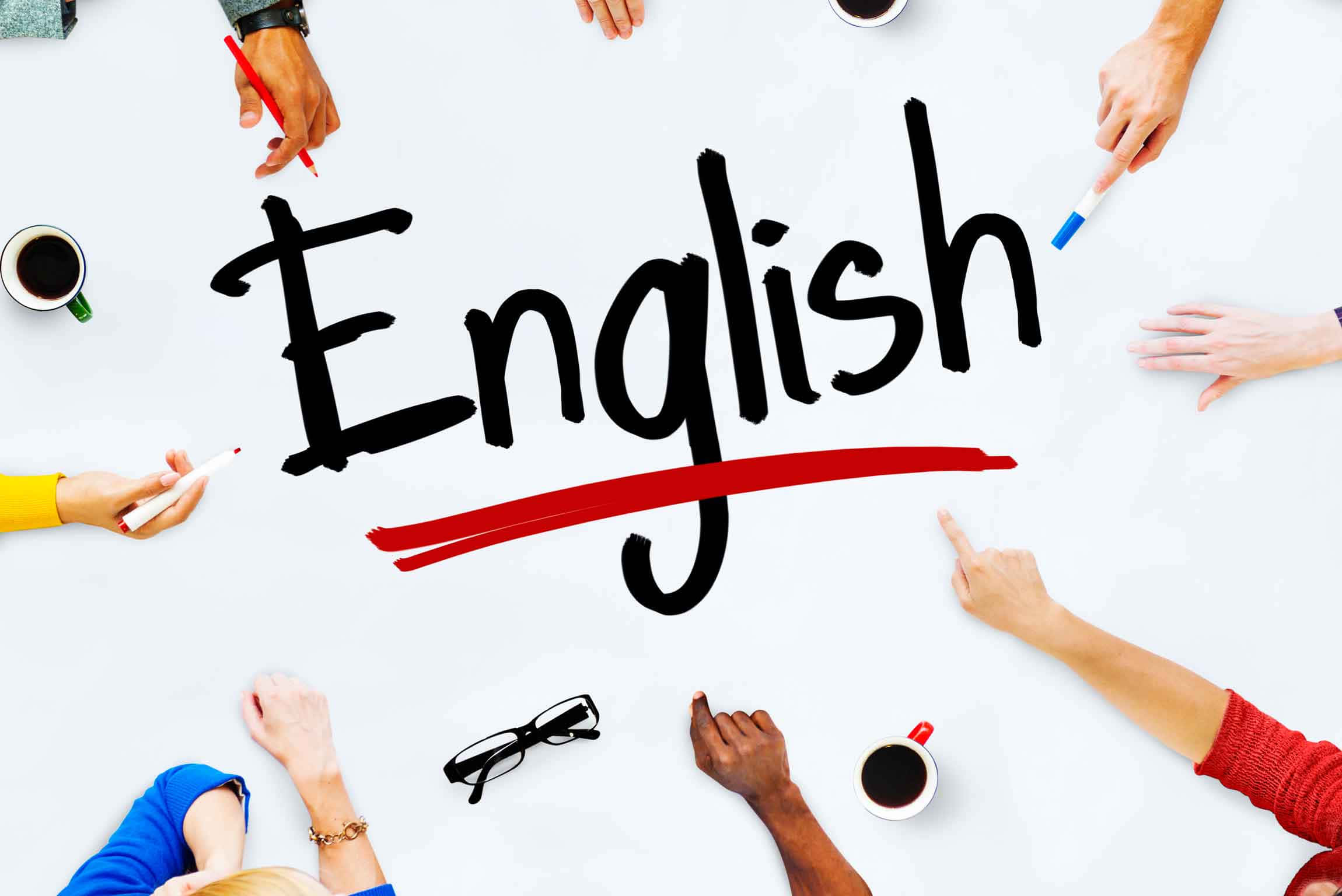 圍繞圓桌學習英語的攝影藝術圖畫 壁紙 — 多隻手圍繞著白色表面上用粗黑馬克筆書寫並帶有紅色底線的「English」一詞。
