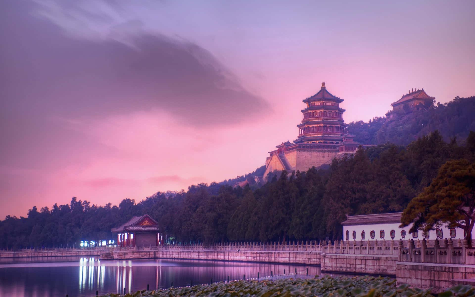 圓明園紫霞夕照 壁紙 — 天壇黃昏時分的寧靜景象，粉紅色的天空倒映在平靜的水面上，四周環繞著茂密的綠樹。