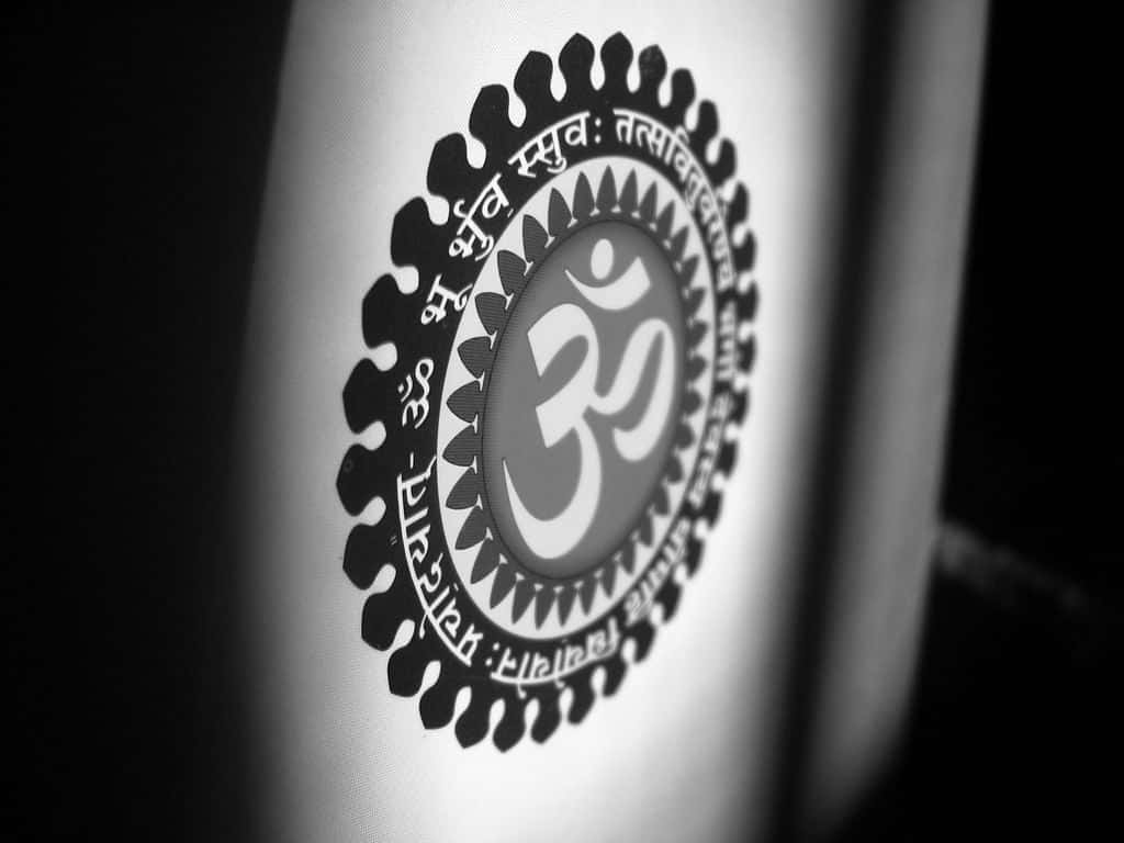 Om 桌布 壁紙 — 圓柱形表面上被梵文環繞的神聖Om符號的特寫黑白照片。
