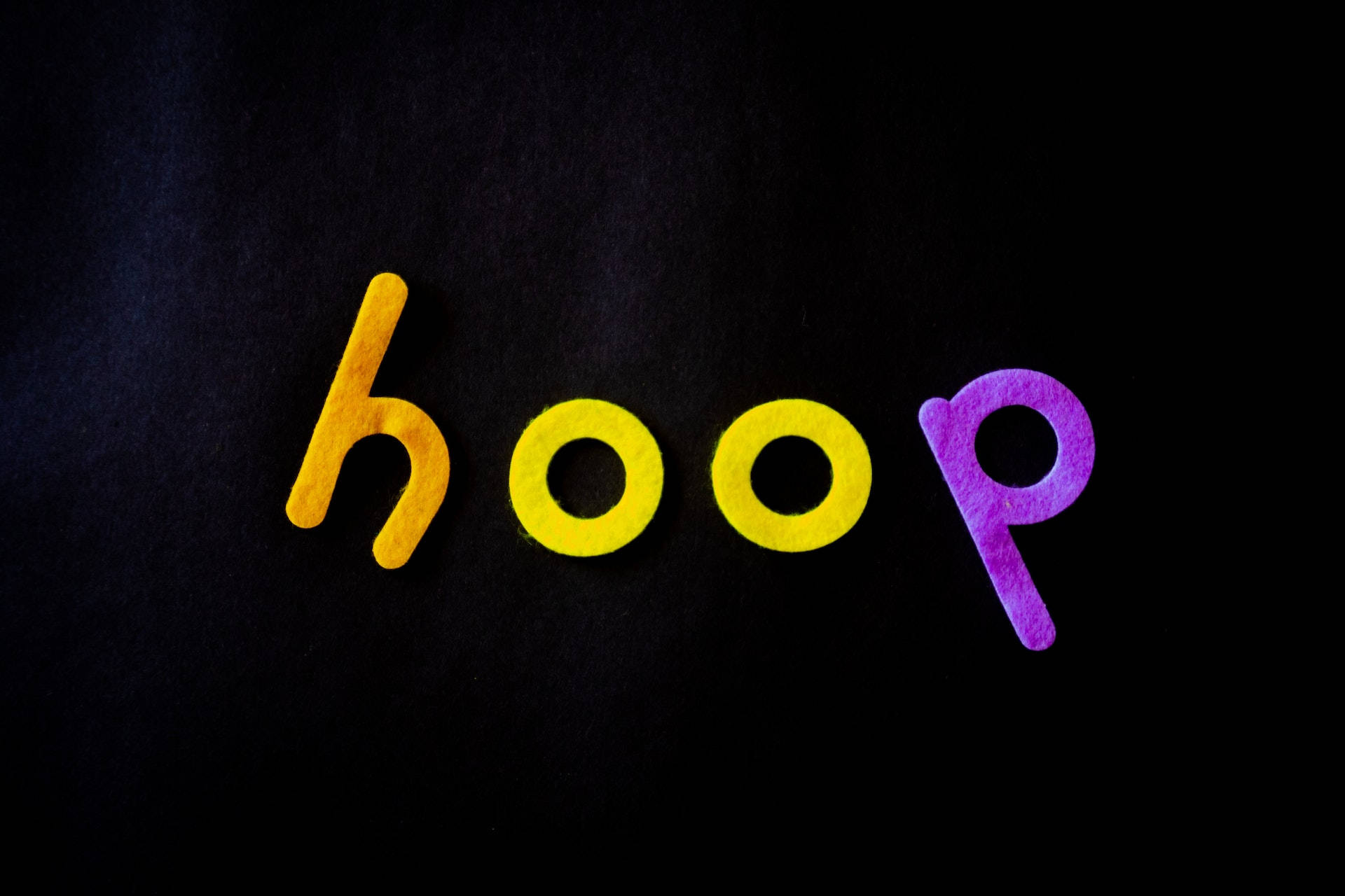 在深色背景上用彩色氈布字母組成的單詞 hoop。