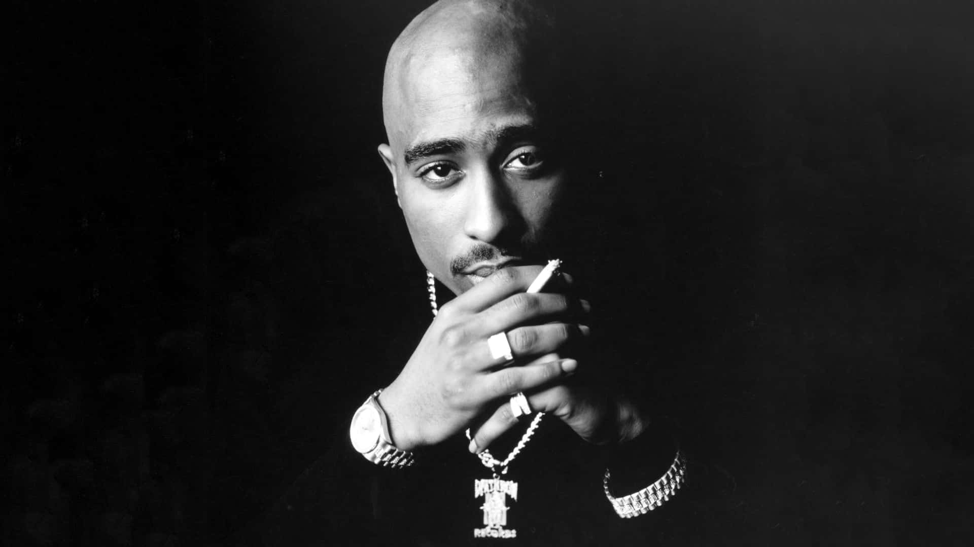 Tupac Shakur 在黑白工作室肖像中手持香煙。
