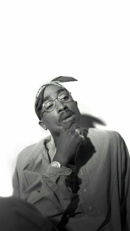 Tupac Shakur 的黑白肖像，戴著頭巾和眼鏡，手托下巴。