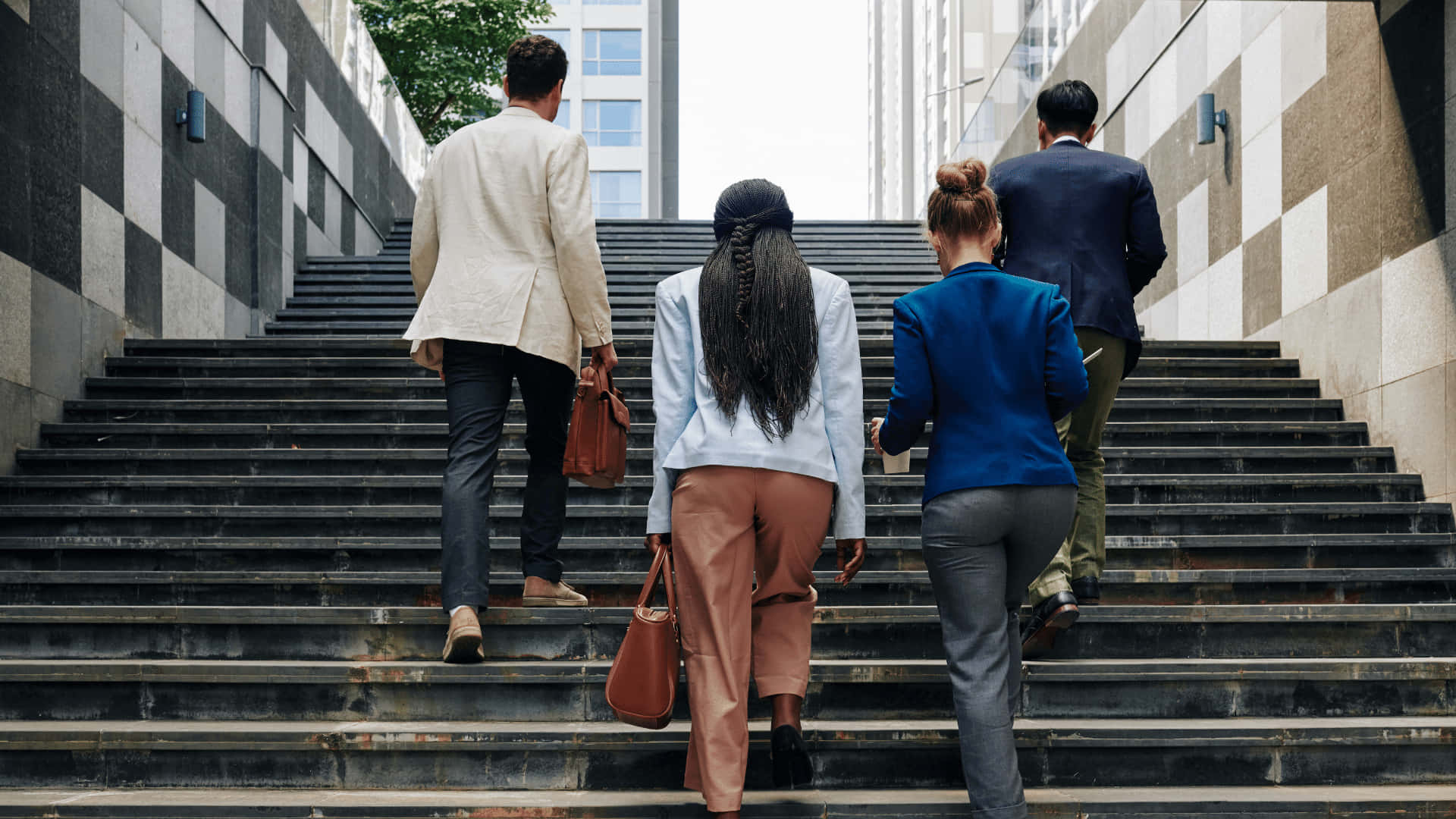 四位穿著商務服裝的專業人士正在攀登城市樓梯。