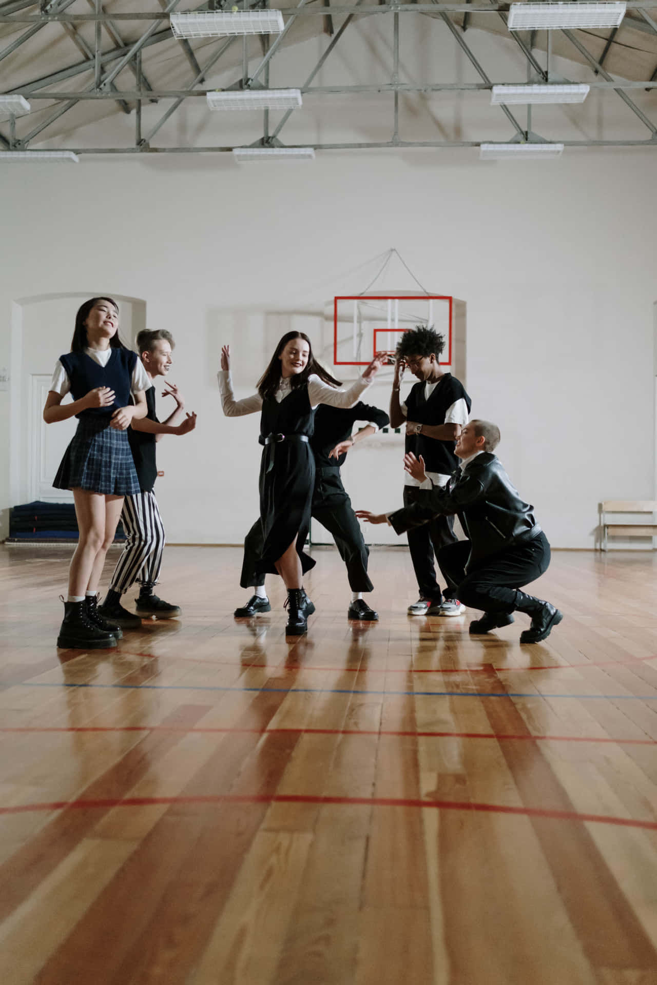五名身穿校服的青少年在體育館內跳舞。