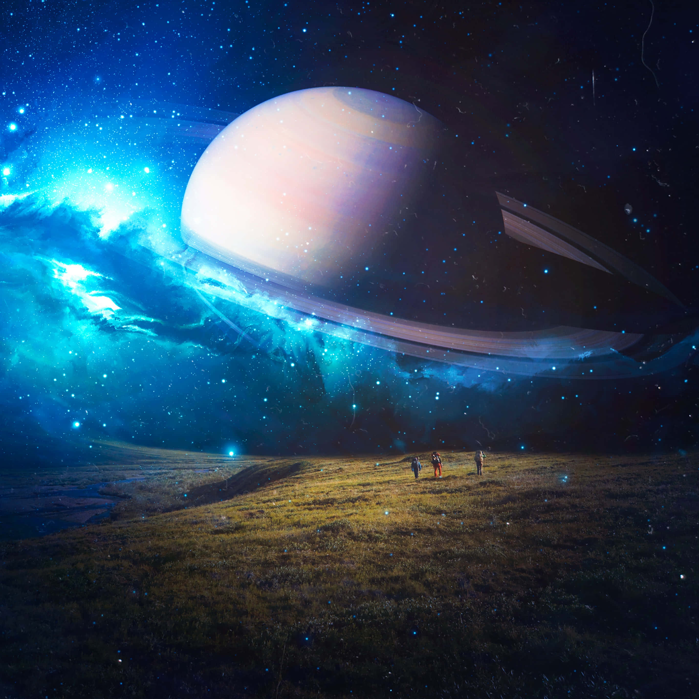 土星在深邃宇宙中閃耀 壁紙 — 三個微小的人物站在一片草地上，上方是一個巨大的土星，散發著宇宙藍色星雲和星星的光芒。