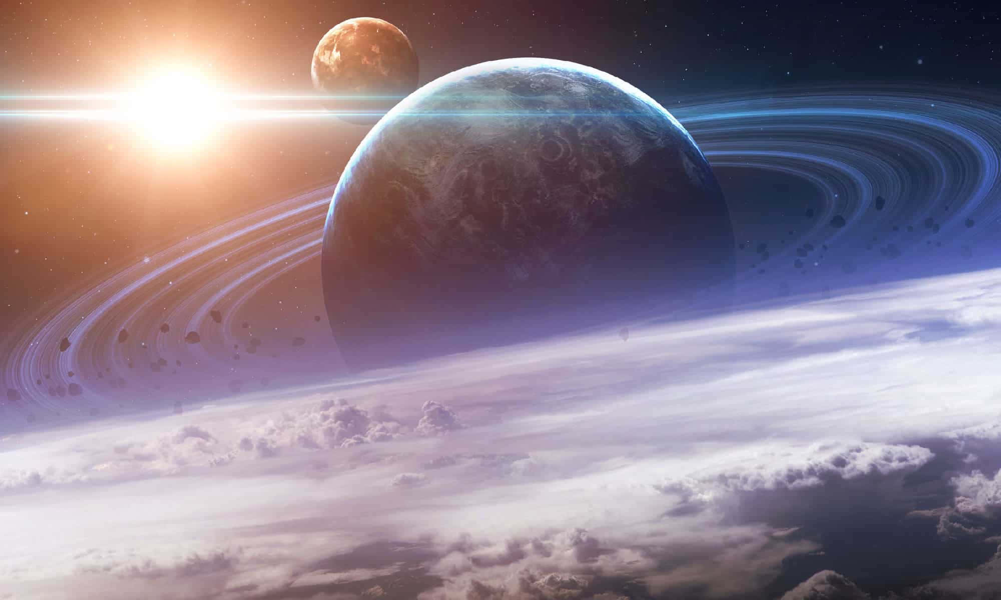 土星與其環系的迷人風景，雲層環繞 壁紙 — 一顆宏偉的環狀行星在燦爛的太陽下發光，下方有遙遠的月球和旋轉的雲層。