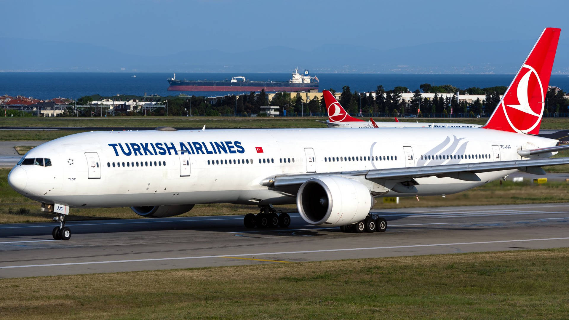 土耳其航空飛機在跑道上，背景有海洋和貨船。 — 飛機 壁紙