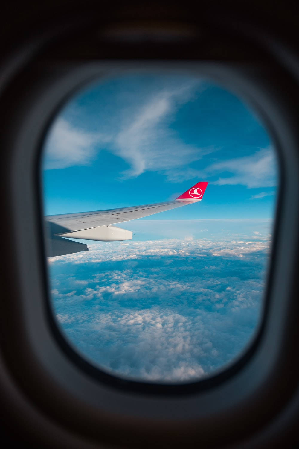 晴朗天氣下透過窗戶看到雲層上方的飛機機翼