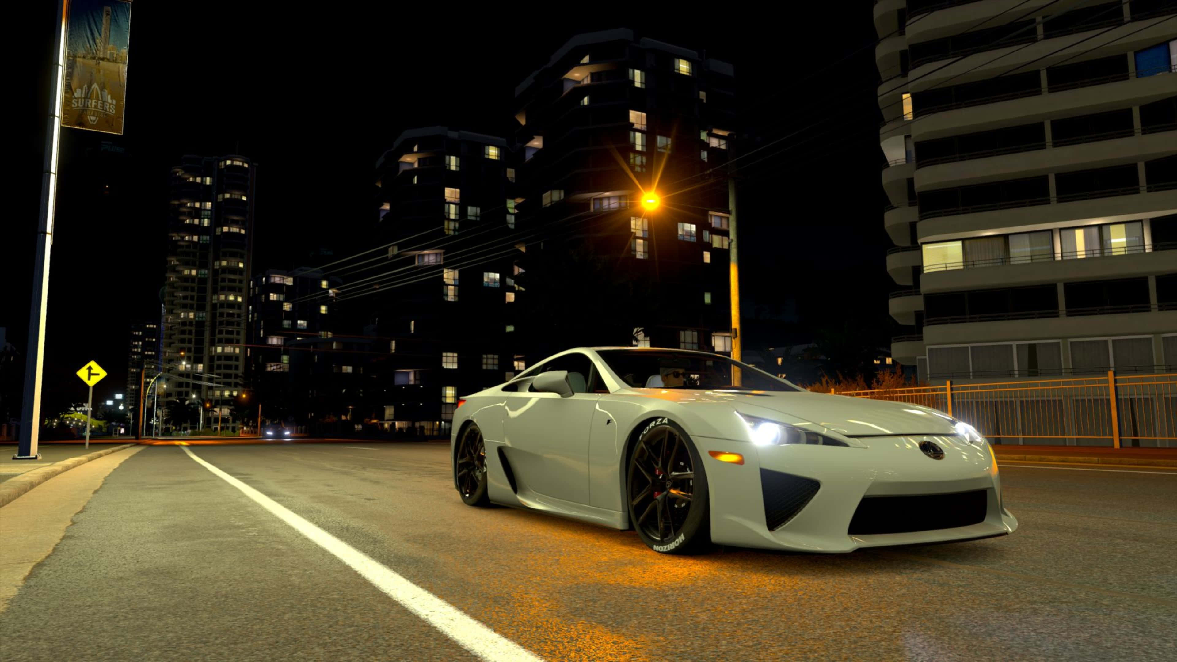在 4K 分辨率中感受《Forza Motorsport 7》賽車的刺激 壁紙 — 一輛時尚的白色跑車在夜晚沿著霓虹燈閃爍的城市街道滑行，背後是高聳發光的建築物。