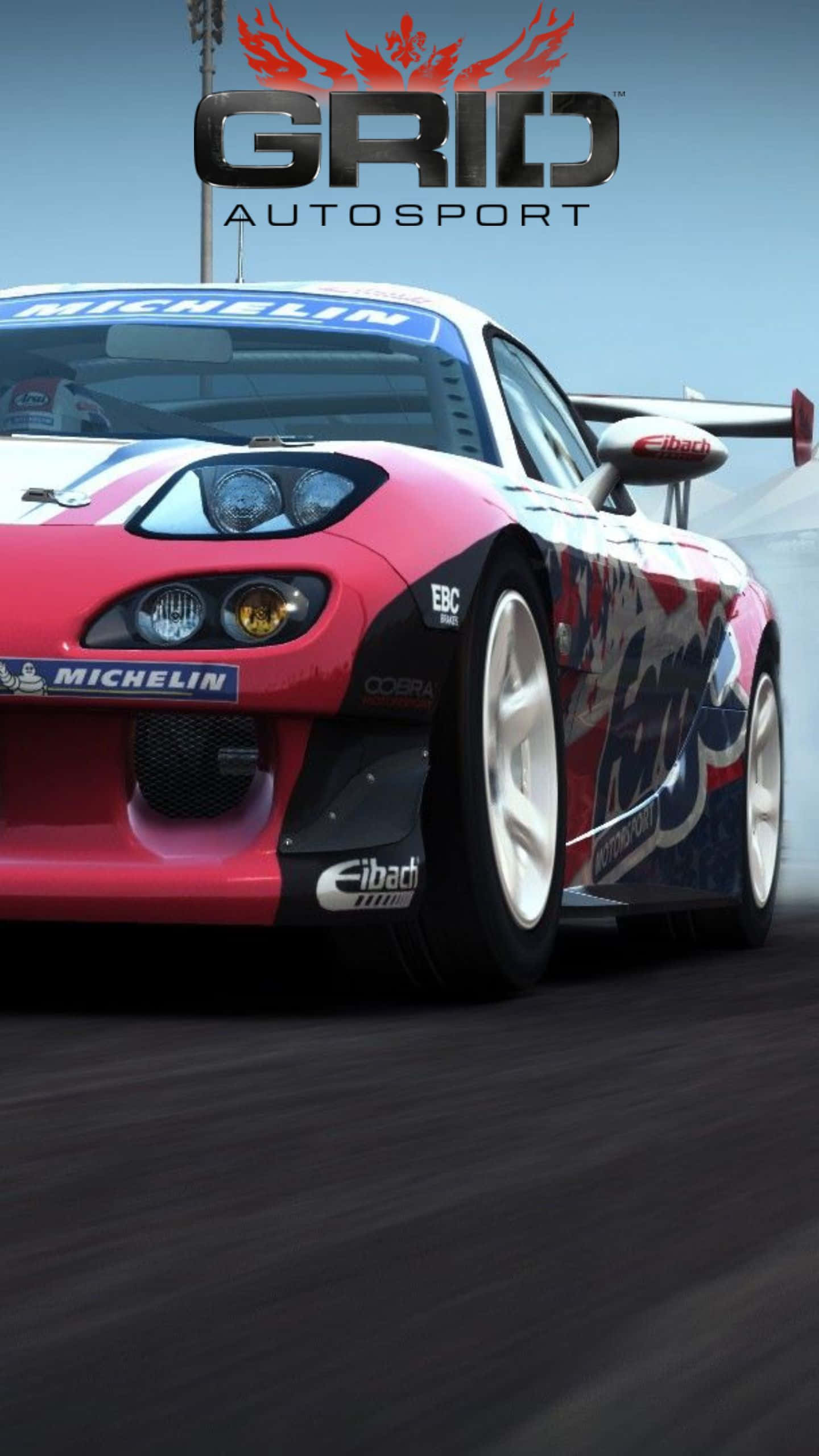 在 Android Grid Autosport 中疾馳過彎道 壁紙 — 一輛紅藍賽車在賽道上疾馳，帶有動態模糊和可見的贊助商標誌。