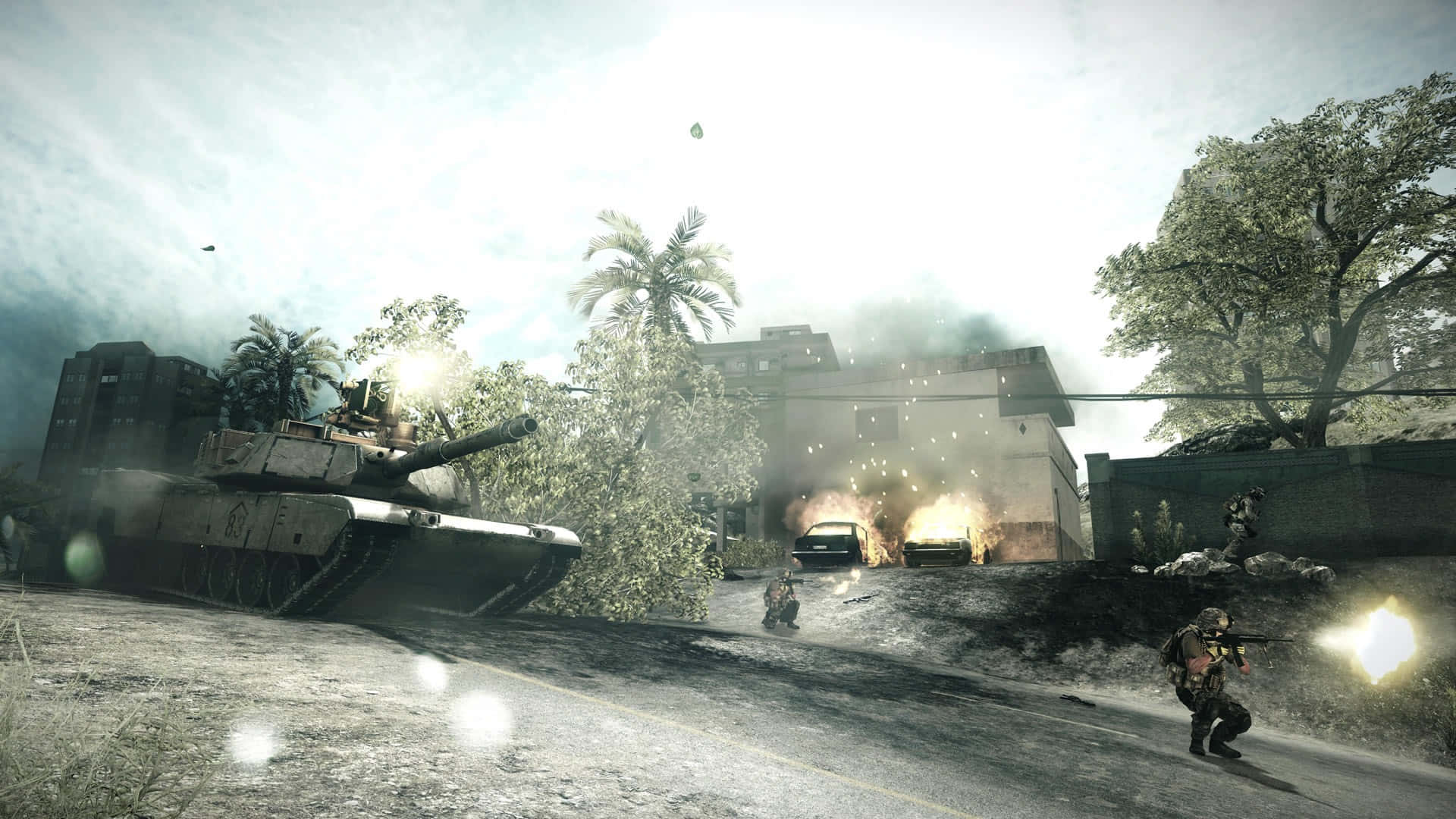 在《Battlefield 3》中主宰戰場 壁紙 — 一輛軍用坦克主宰著陽光普照的熱帶戰場，士兵們在燃燒的車輛和棕櫚樹中交戰。