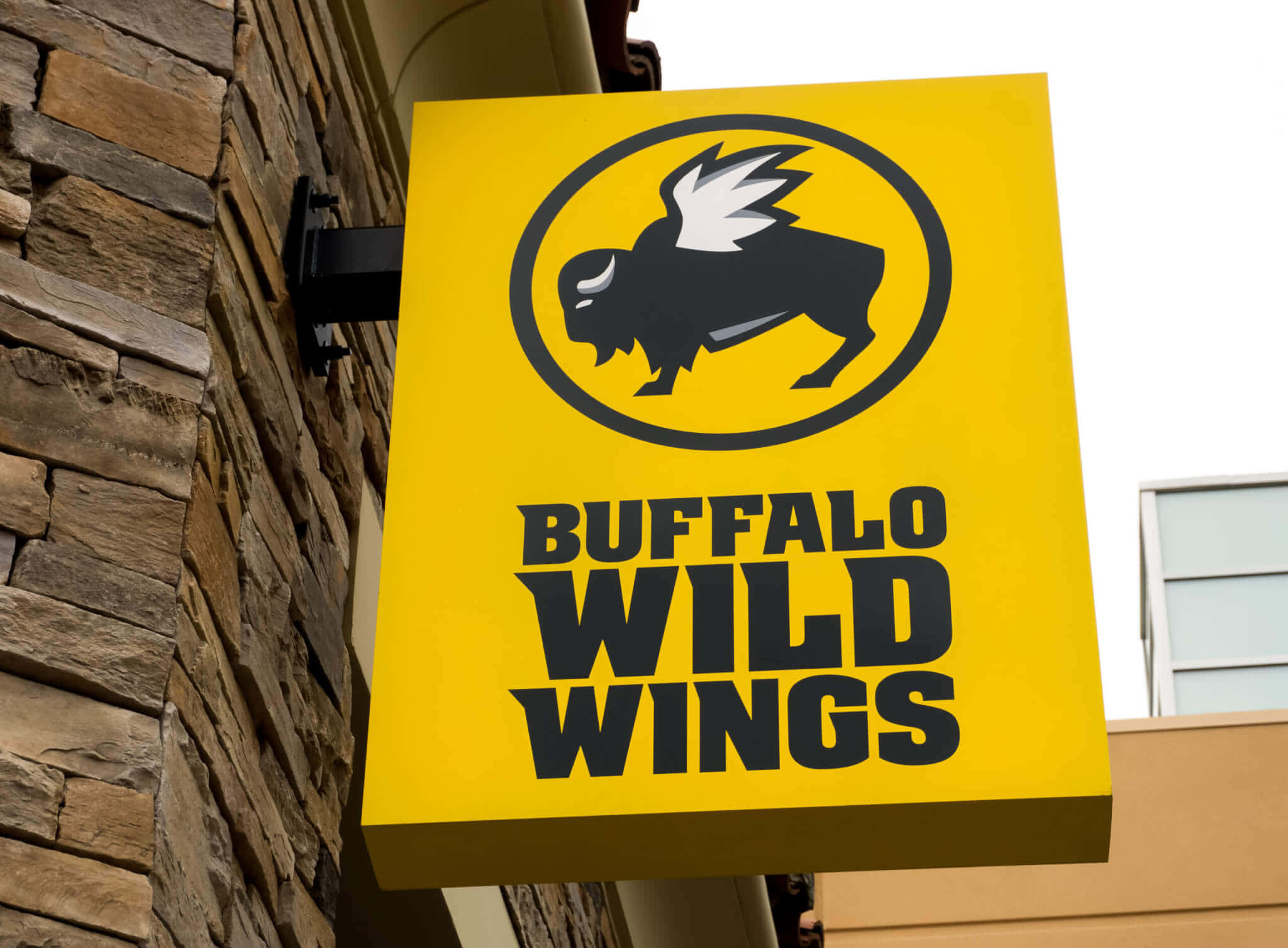 黃色Buffalo Wild Wings餐廳招牌安裝在石頭建築上。