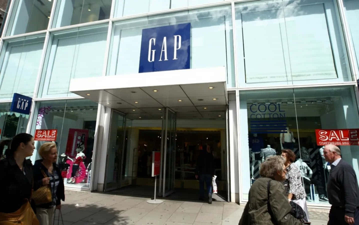 購物者走過一間GAP服裝店，窗戶上可見減價標誌。