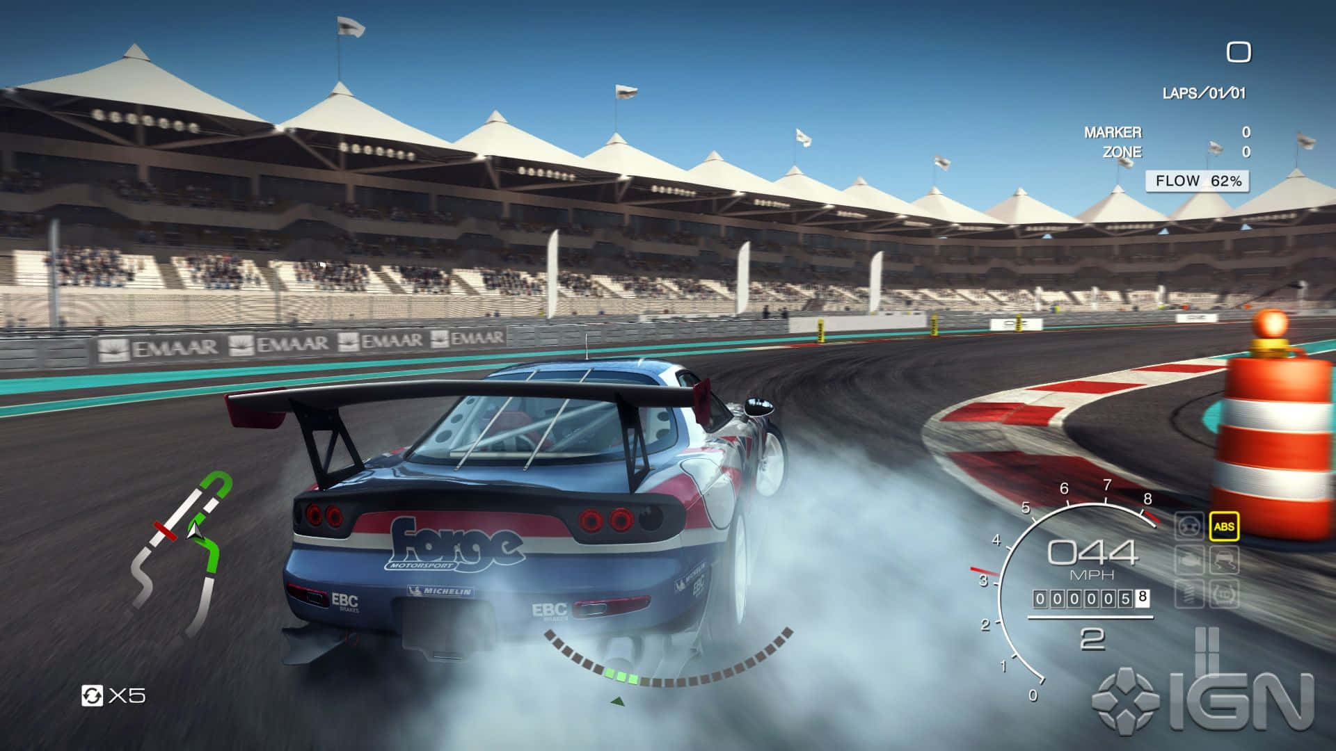 在 Grid Autosport 中超越競爭對手 壁紙 — 一輛藍色賽車在陽光明媚的賽道上繞過彎道漂移，輪胎冒出滾滾濃煙，背景中有看台。