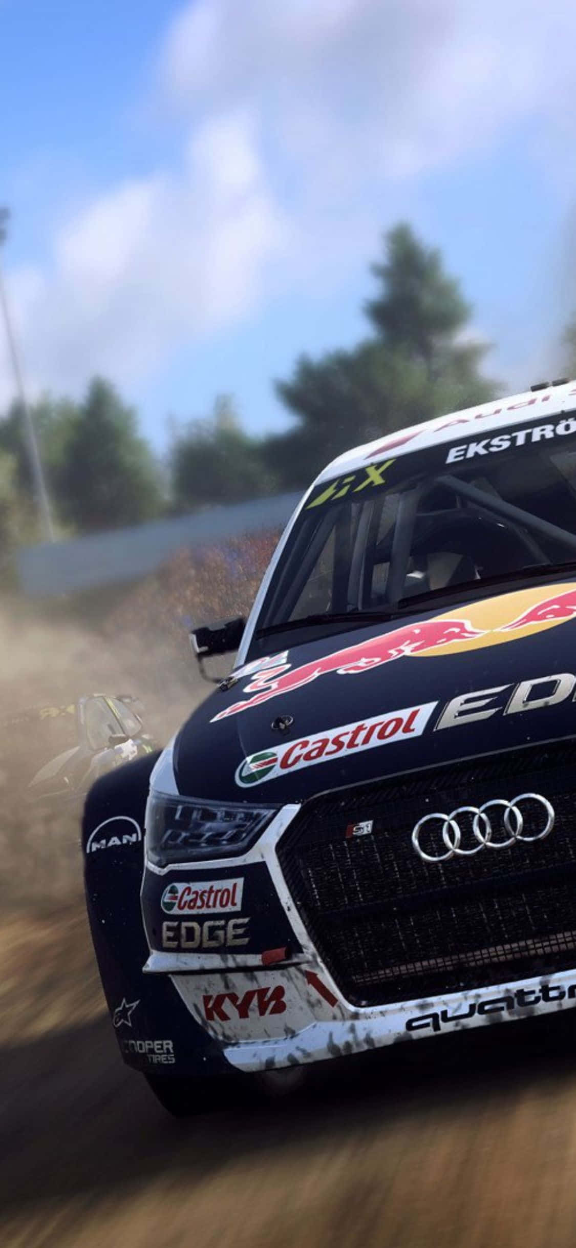 在 iPhone X《Dirt Rally》中於泥地賽道飆馳與漂移 壁紙 — 一輛帶有Red Bull和Castrol標誌的黑色奧迪拉力賽車，在明亮的藍天下疾馳在塵土飛揚的森林小徑上。