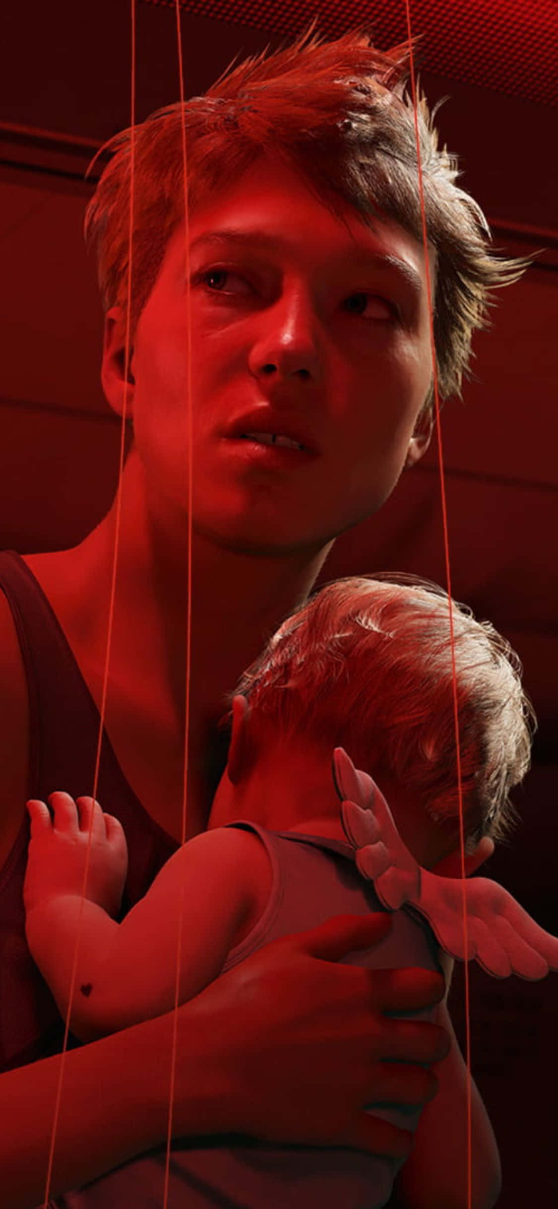 在 iPhone X 上體驗原版《死亡搁淺》遊戲 壁紙 — 一個女人抱著一個嬰兒，紅色的繩子從上方垂下，像木偶線一樣，在一個光線昏暗的房間裡。