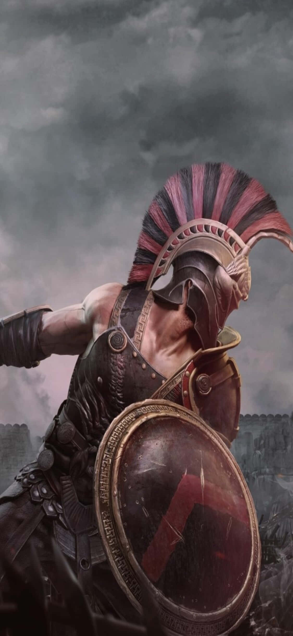 在 iPhone Xs 上征服敵人，統治世界《Total War: Rome 2》 壁紙 — 一名身穿精細青銅盔甲和紅色羽飾頭盔的斯巴達戰士，手持圓盾，在暴風雨戰場的天空下準備就緒。