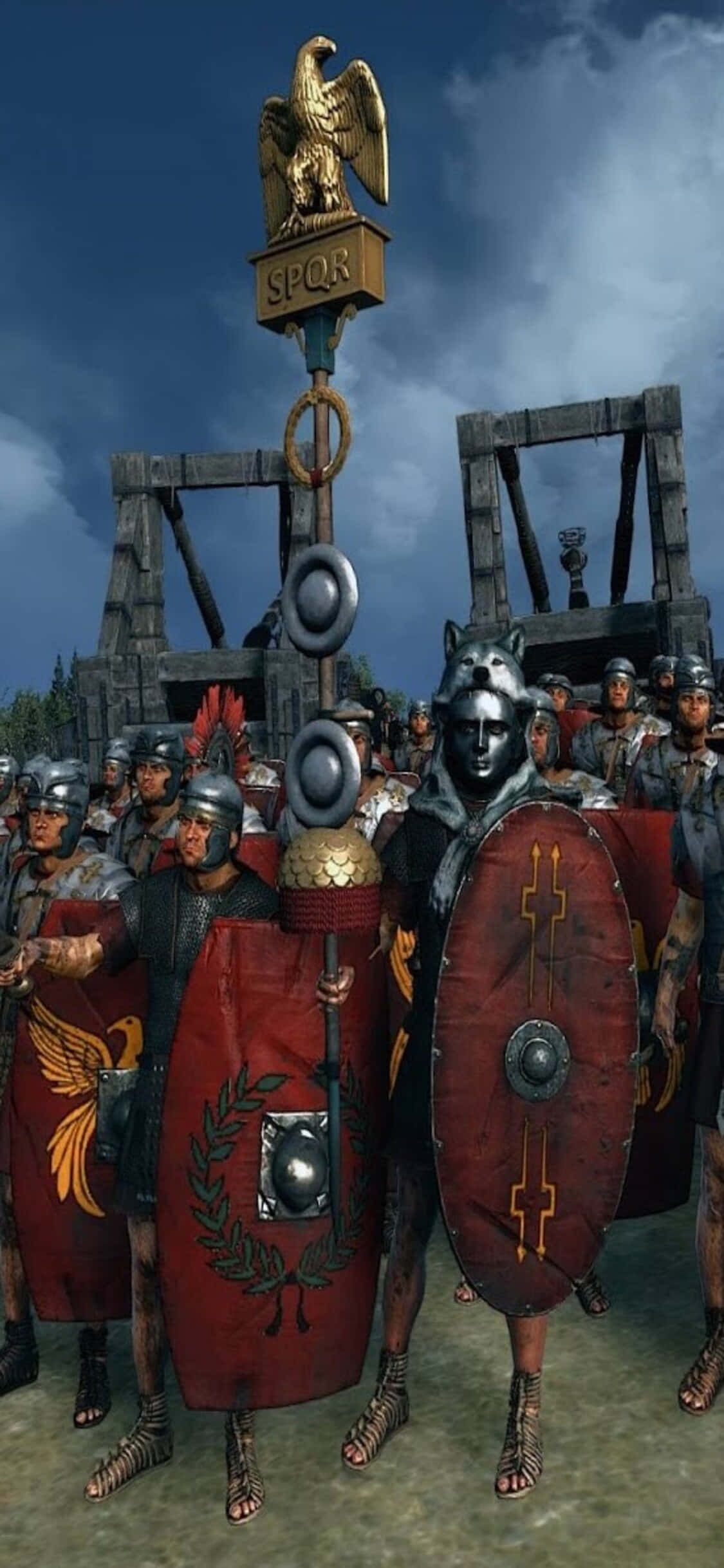 在 iPhone Xs 上指揮部隊，體驗《Total War: Rome 2》 壁紙 — 全副武裝的羅馬軍團士兵在陰雲密布的天空下排列成陣，身後有金色鷹旗和攻城塔。