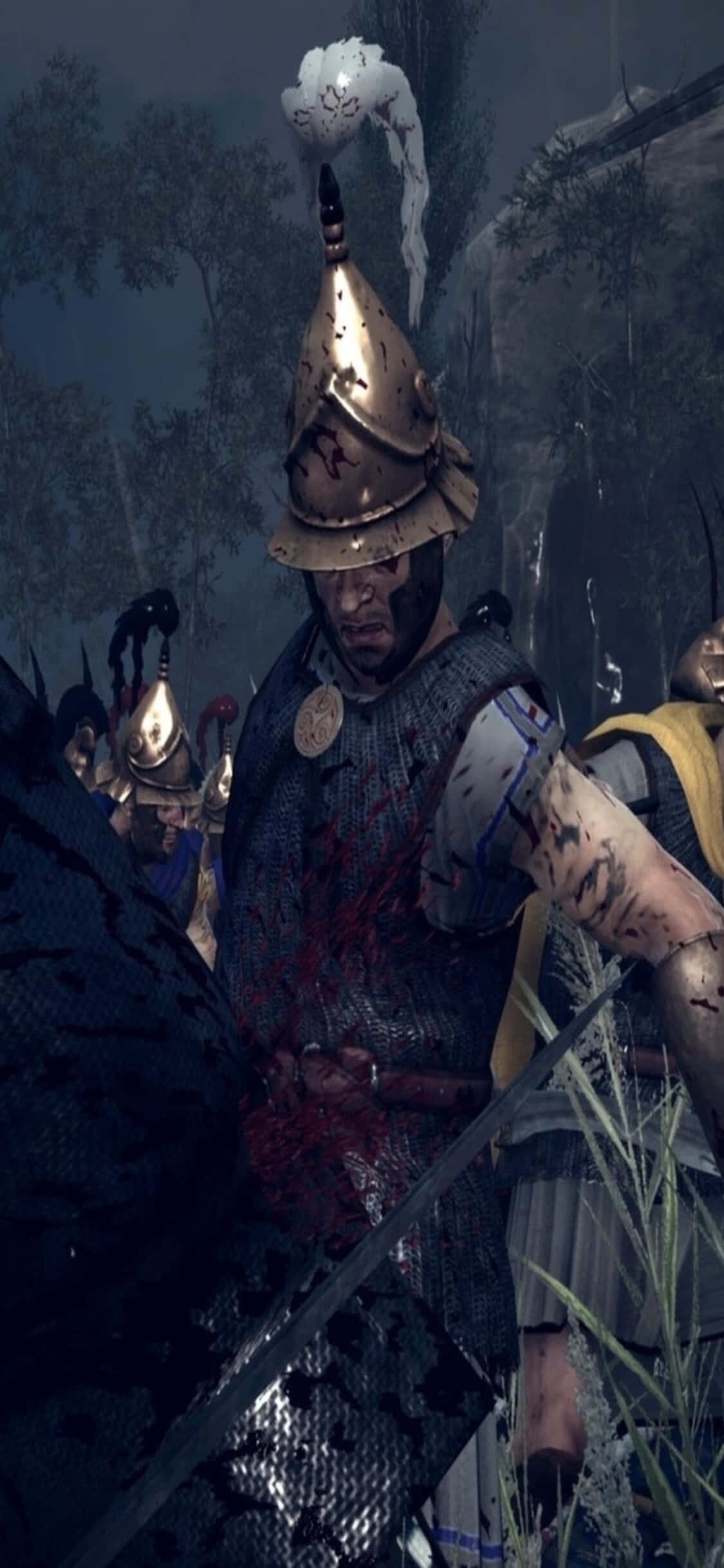 在 iPhone Xs 上體驗《Total War: Rome 2》的壯闊戰爭 壁紙 — 一名血跡斑斑的中世紀士兵戴著華麗的頭盔，站在陰沉的戰場上，頭飾冒出濃煙。