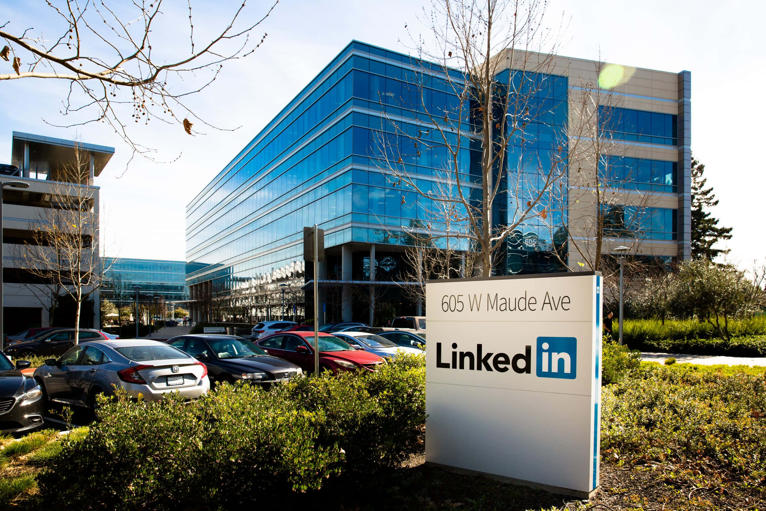 在 LinkedIn 上找到夢想職涯 壁紙 — 現代玻璃LinkedIn辦公大樓，設有顯眼標誌和停車場，在晴朗藍天下。