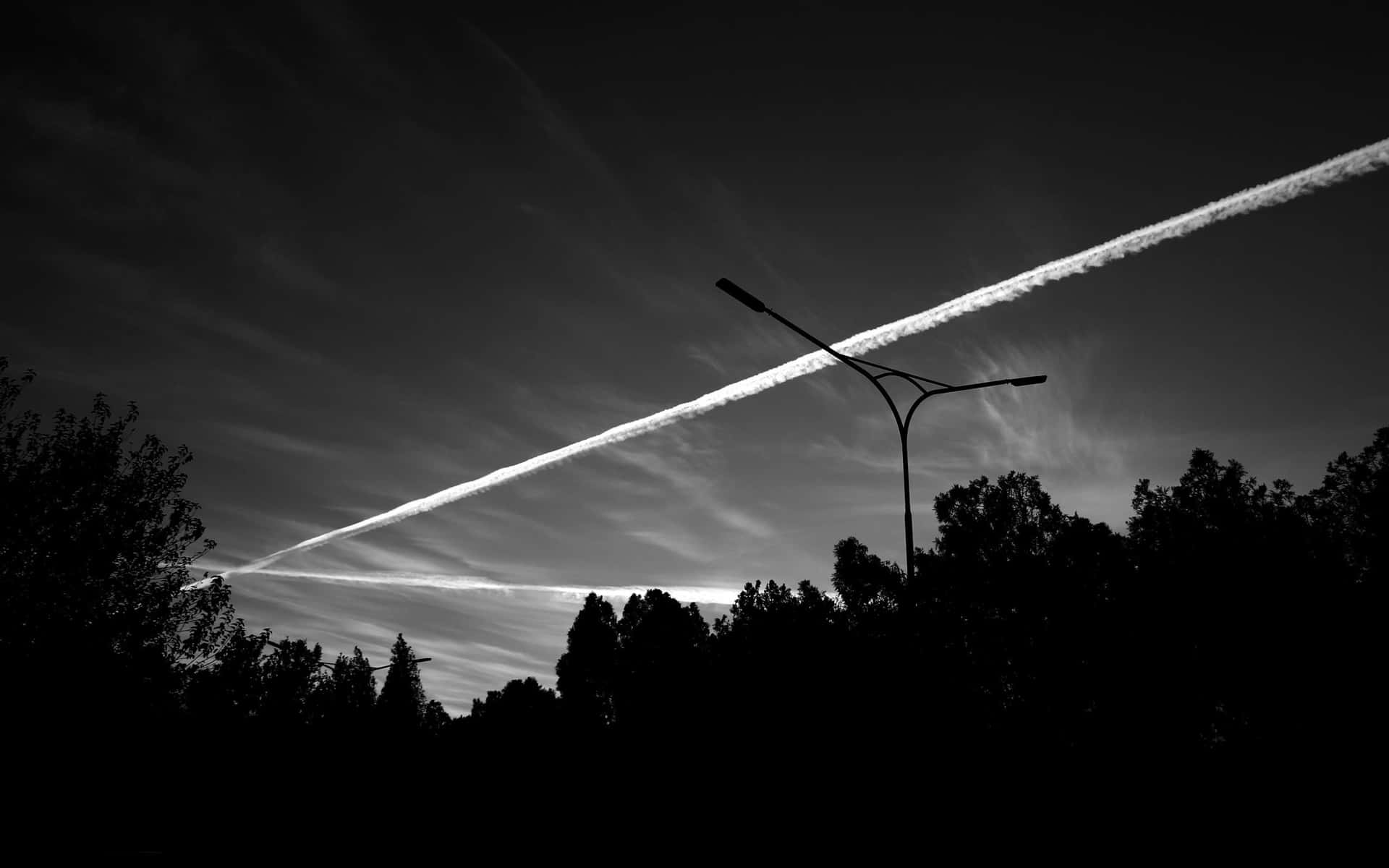 路燈剪影在暮色天空中與飛機凝結尾跡