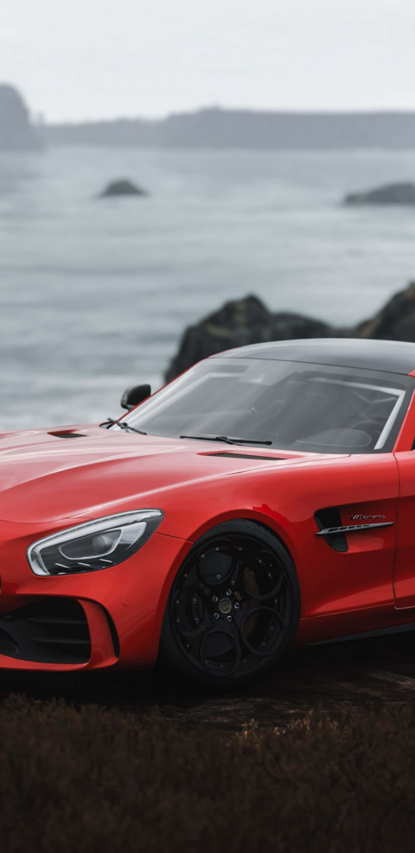 在 Pixel 3XL 上欣賞《Forza Horizon 4》的壯麗地形 壁紙 — 一輛鮮紅色的跑車停泊在長滿草的懸崖上，俯瞰著霧氣瀰漫的海洋和遠處的岩石海岸。