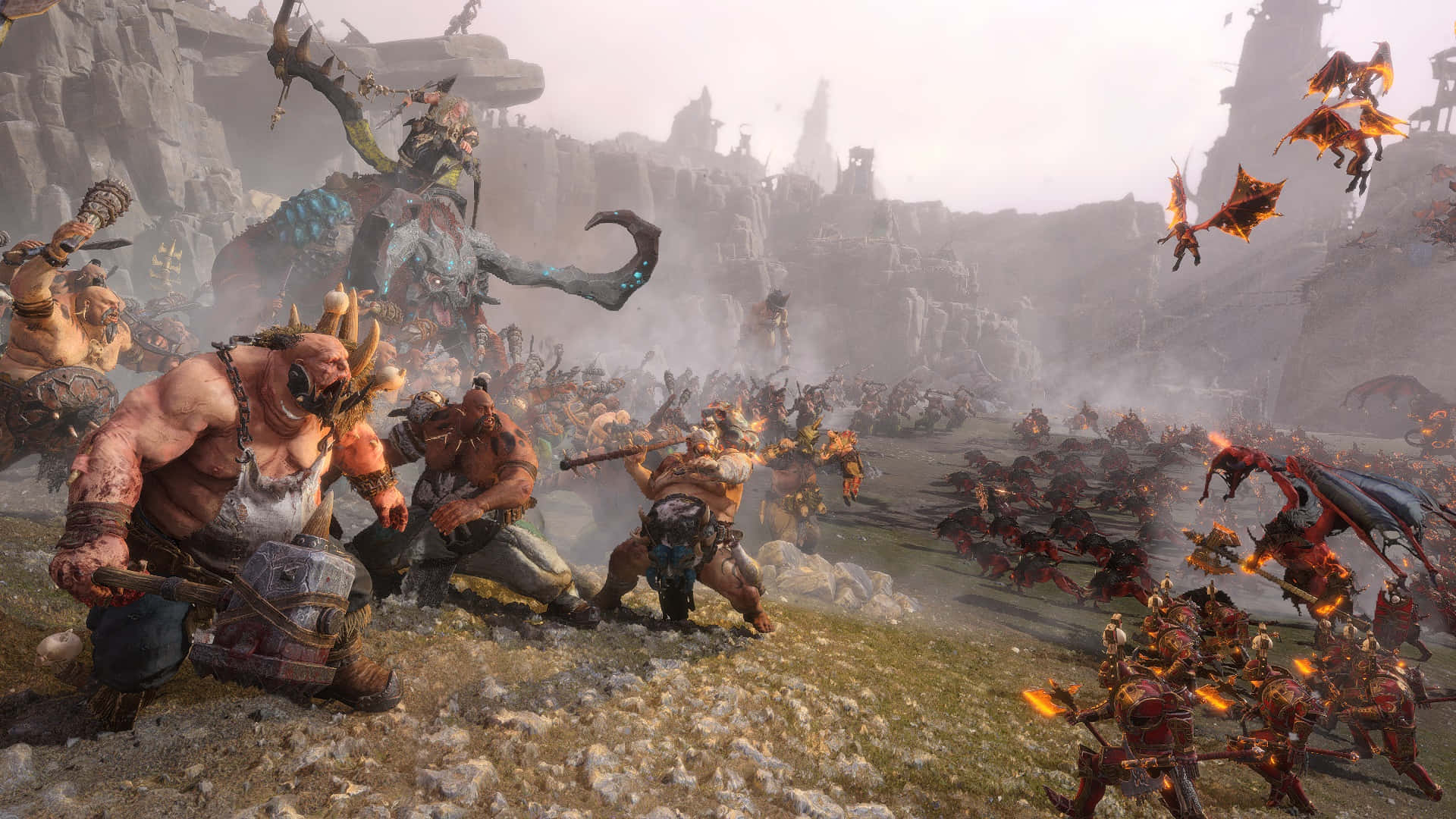 在《Total War: Warhammer》中展開壯闊戰役 壁紙 — 一個巨大的獸人 warlord 在霧氣瀰漫的山地戰場上，帶領一場混亂的戰鬥，對抗裝甲士兵和飛龍。