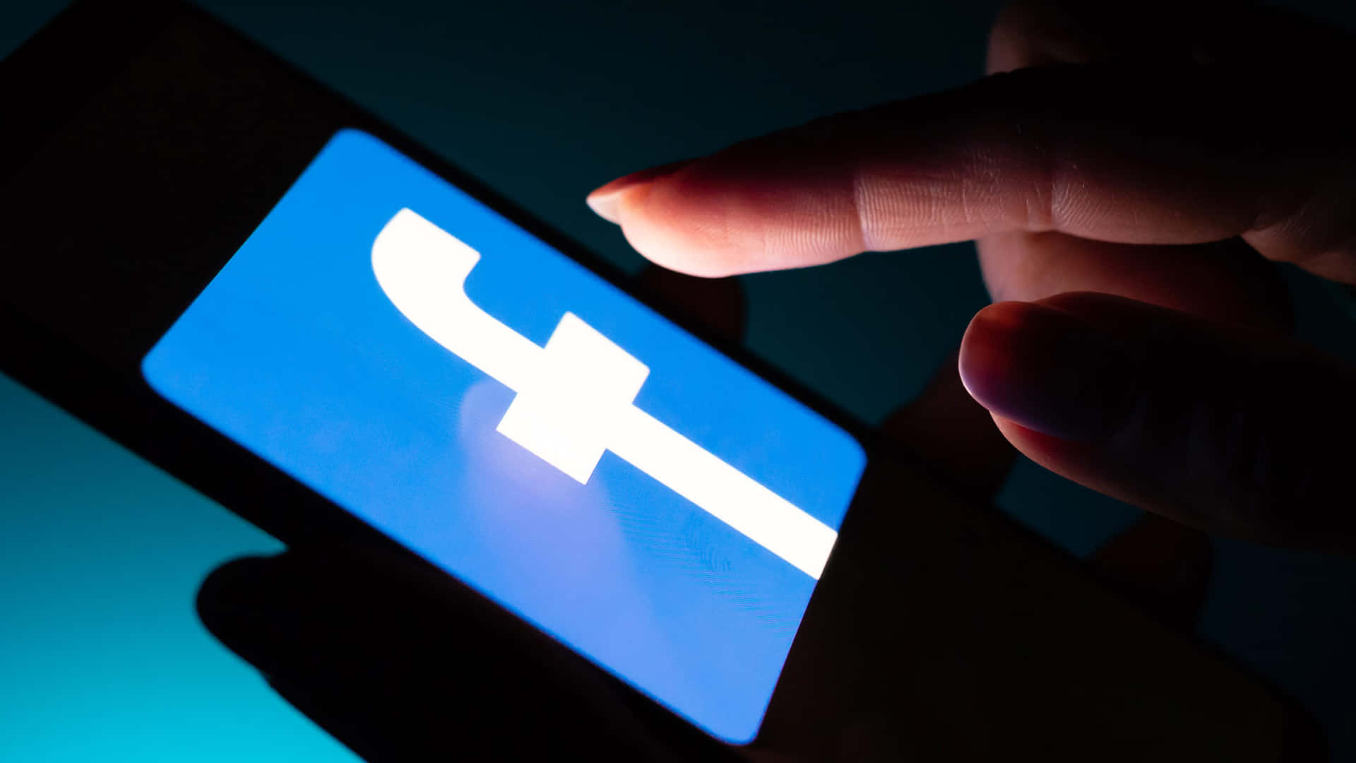 在黑暗的房間中點擊智能手機上的Facebook應用程式的手