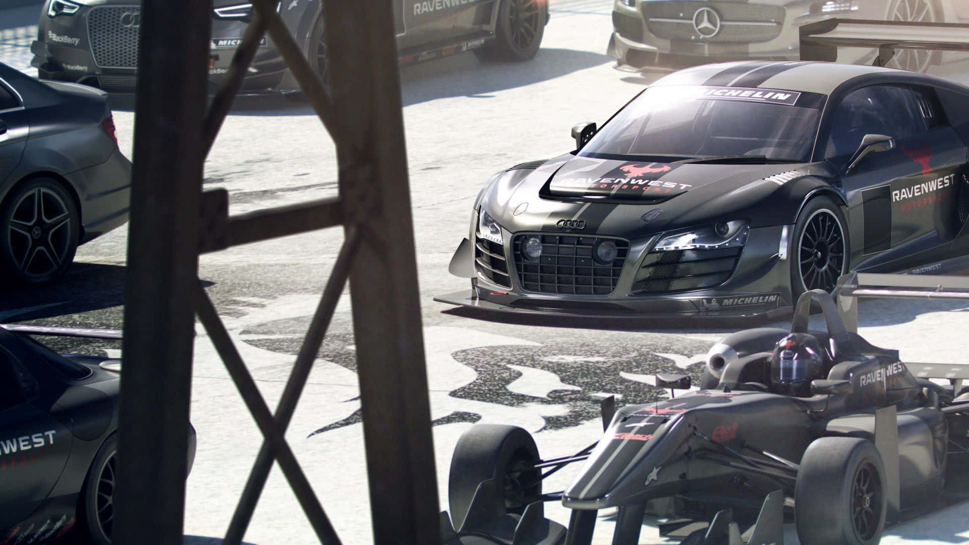 在Grid Autosport中全速衝刺 壁紙 — 一架時尚的黑色奧迪R8賽車和一輛一級方程式賽車停放在陽光明媚的維修區車道上，其他高性能車輛也清晰可見。