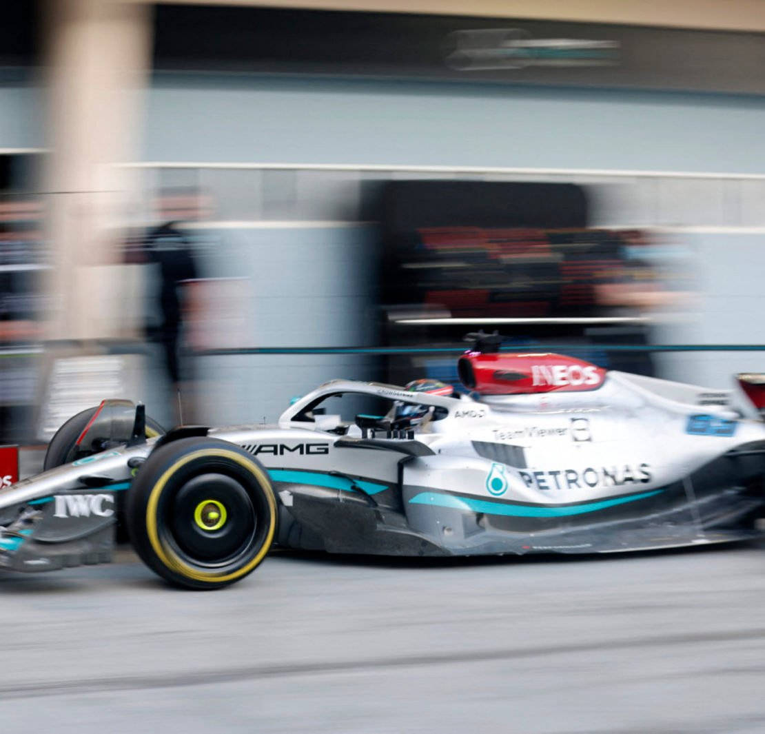 一輛高速F1賽車在街道賽道上飛馳，帶有動態模糊效果。