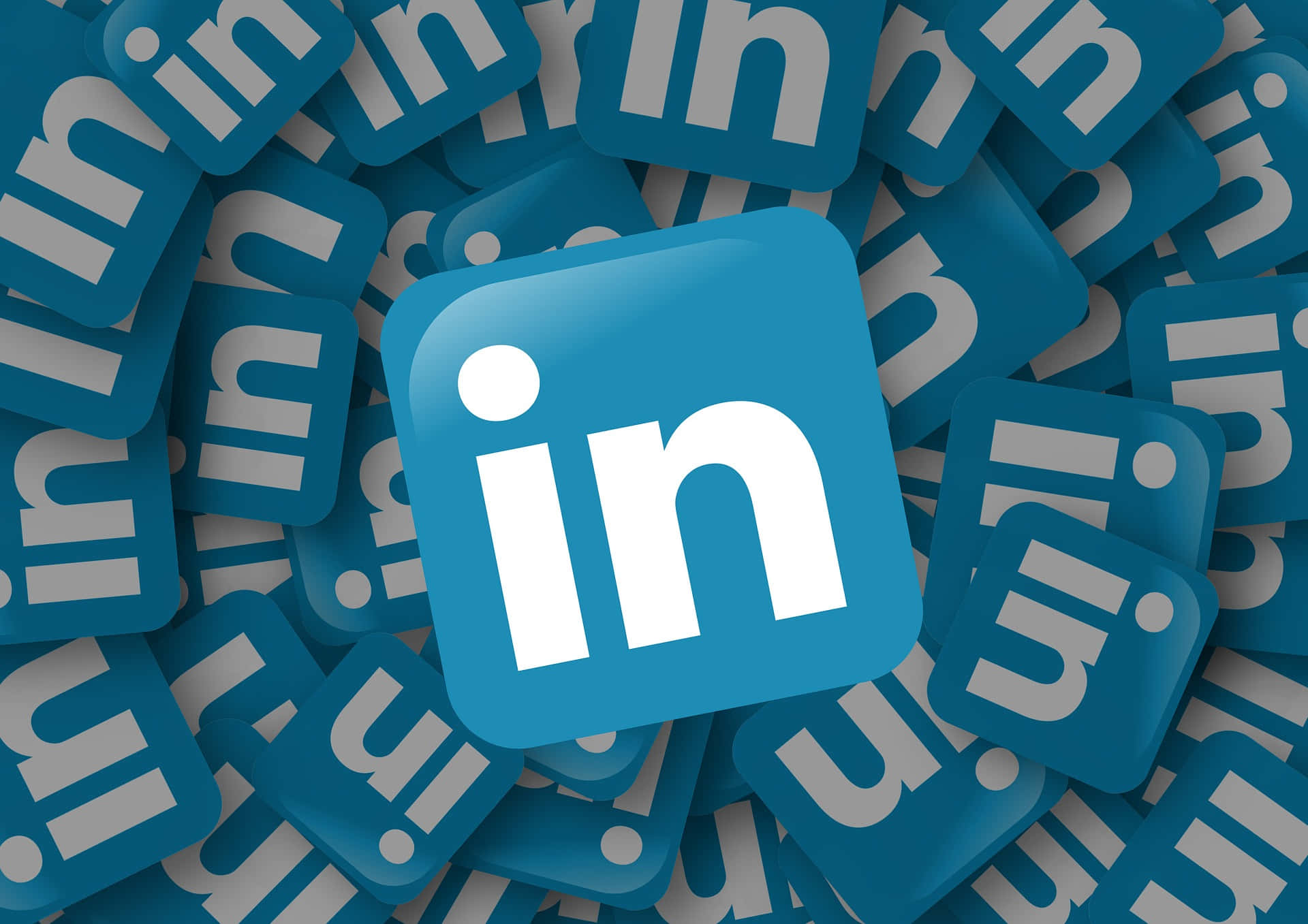 在LinkedIn上實現最大能見度與影響力 壁紙 — 中央的 LinkedIn 標誌被重疊的藍色 LinkedIn 圖示包圍，形成密集的數位圖案。