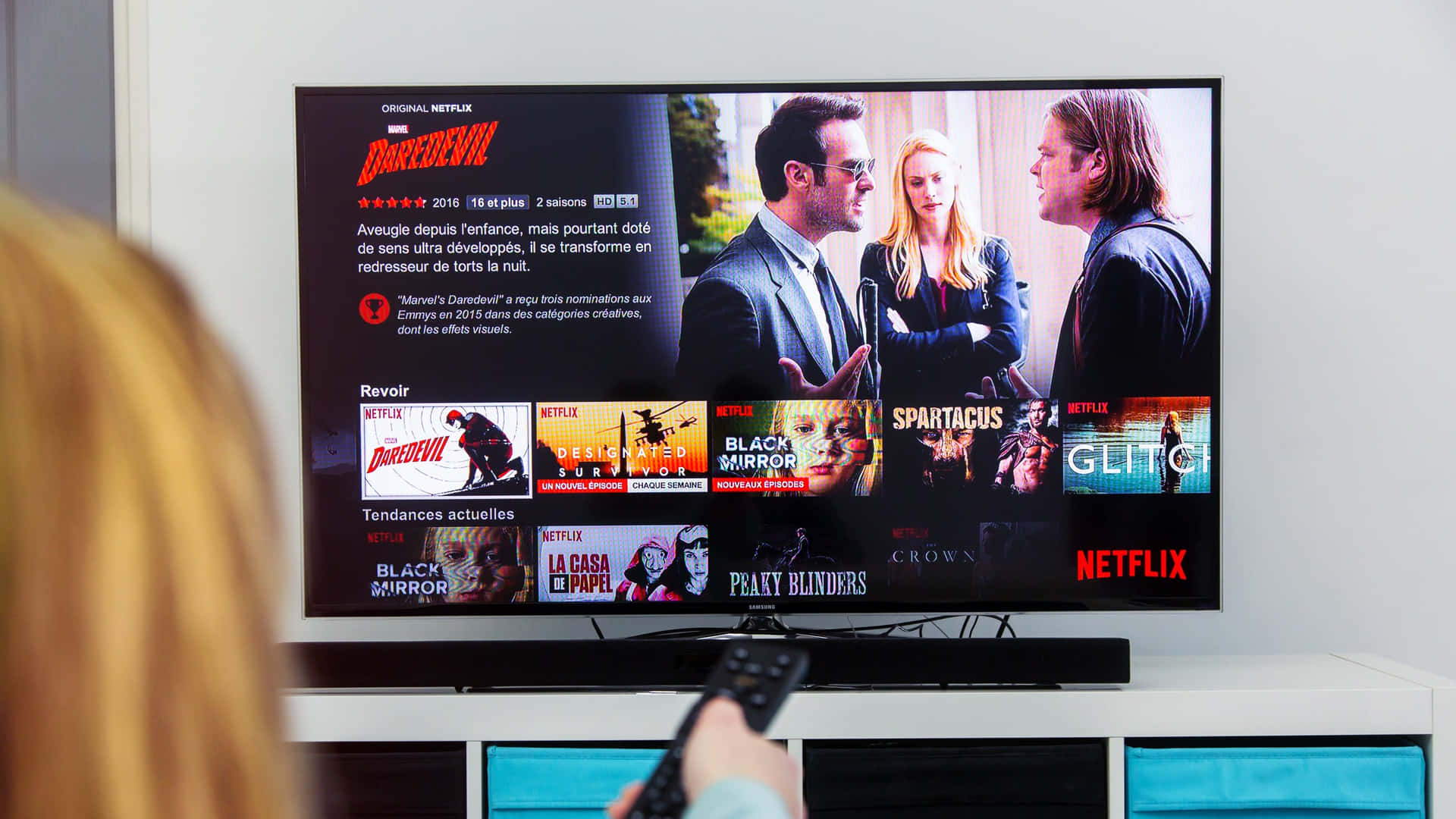 揸住遙控器嘅人睇緊Netflix電視顯示Daredevil節目頁面。