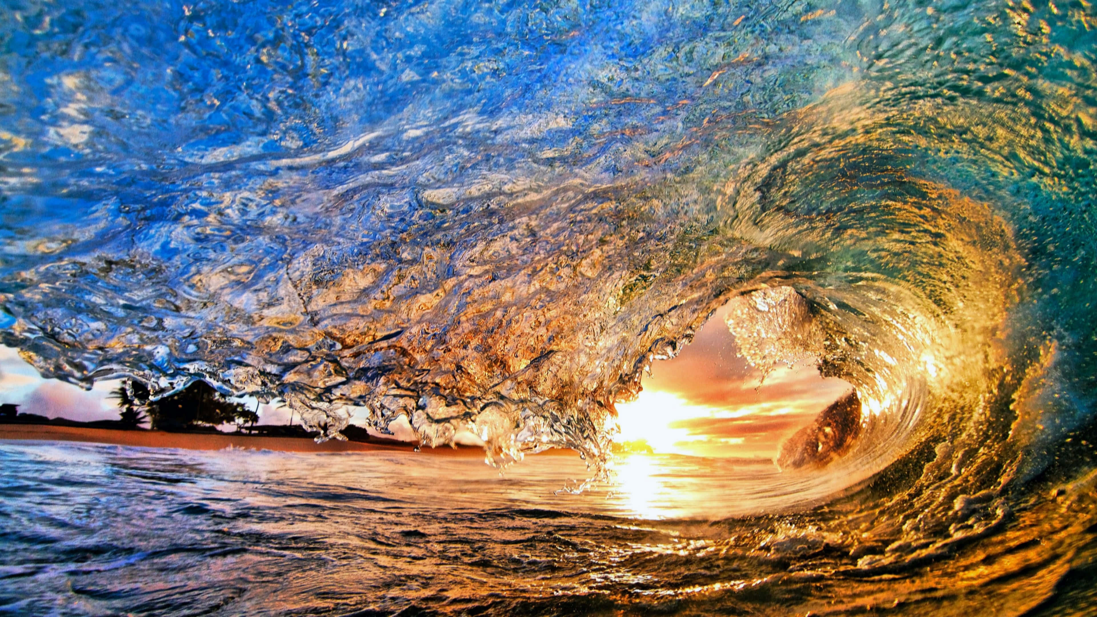 在UHD上欣賞壯麗景色 壁紙 — 巨大的海浪在日落時分在頭頂捲曲，透過其半透明的桶狀顯露出閃爍的金色地平線。