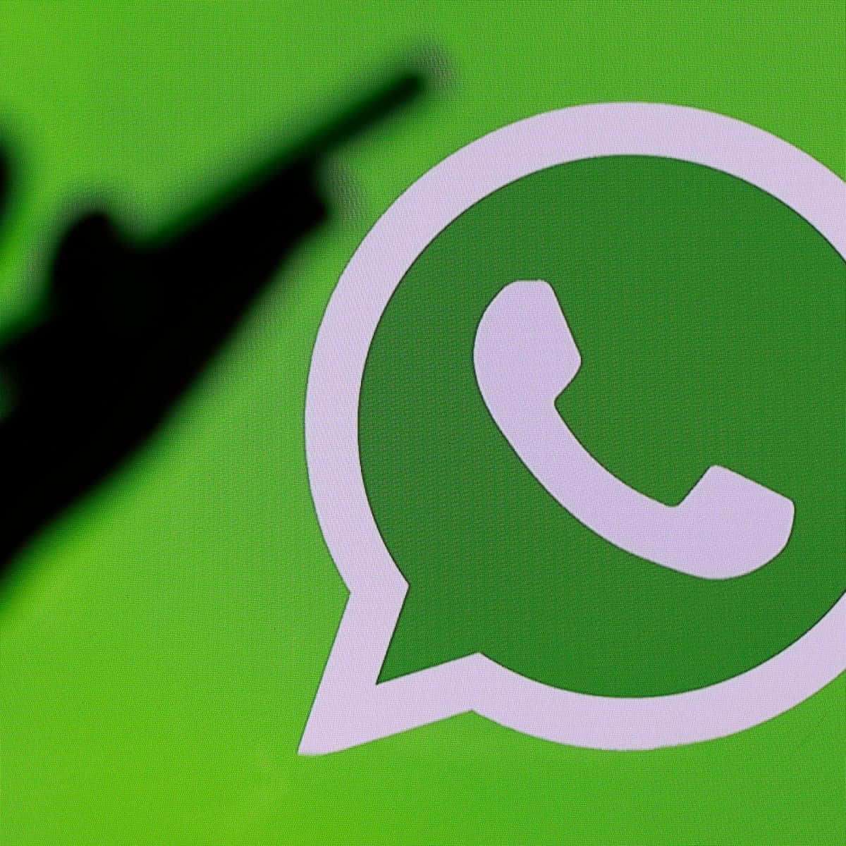 一個 WhatsApp 標誌，有一隻模糊的手指指向它。