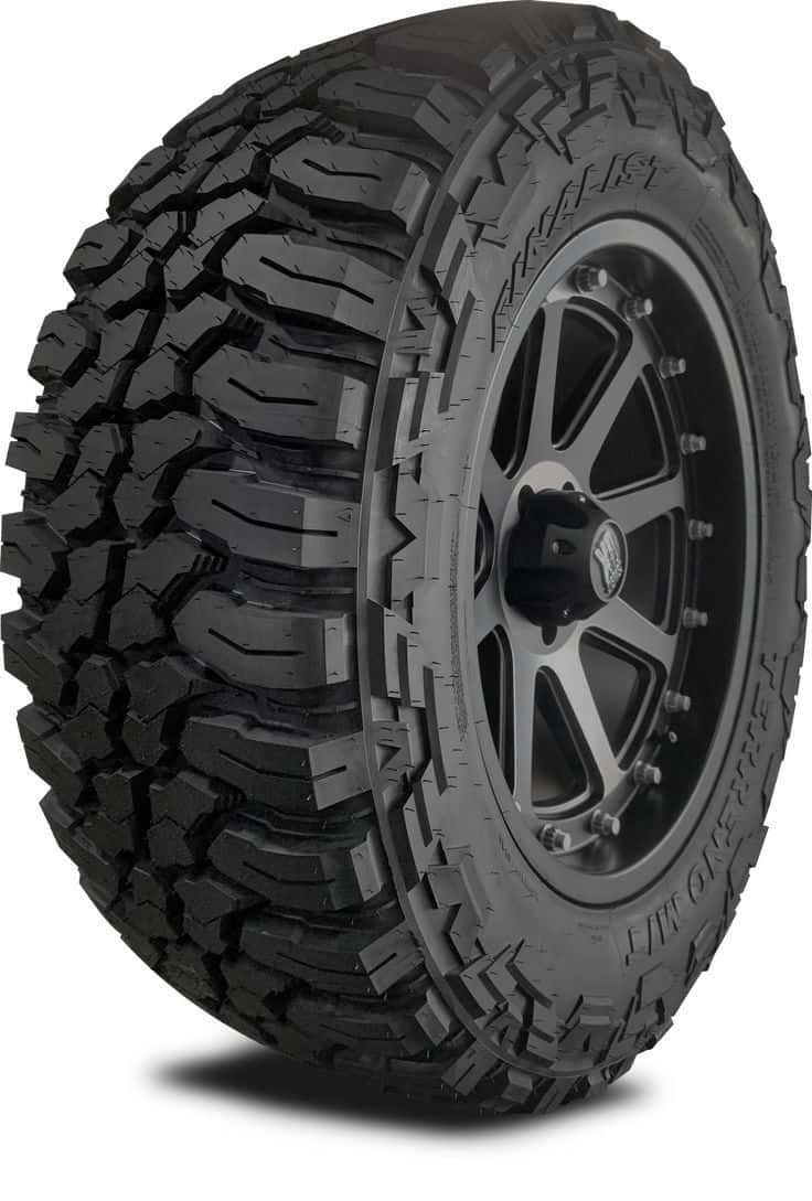 Winter Tires 桌布 壁紙 — 在乾淨的白色背景上，一個堅固的黑色全地形輪胎安裝在磨砂黑色多輻輪圈上的特寫攝影棚照片。
