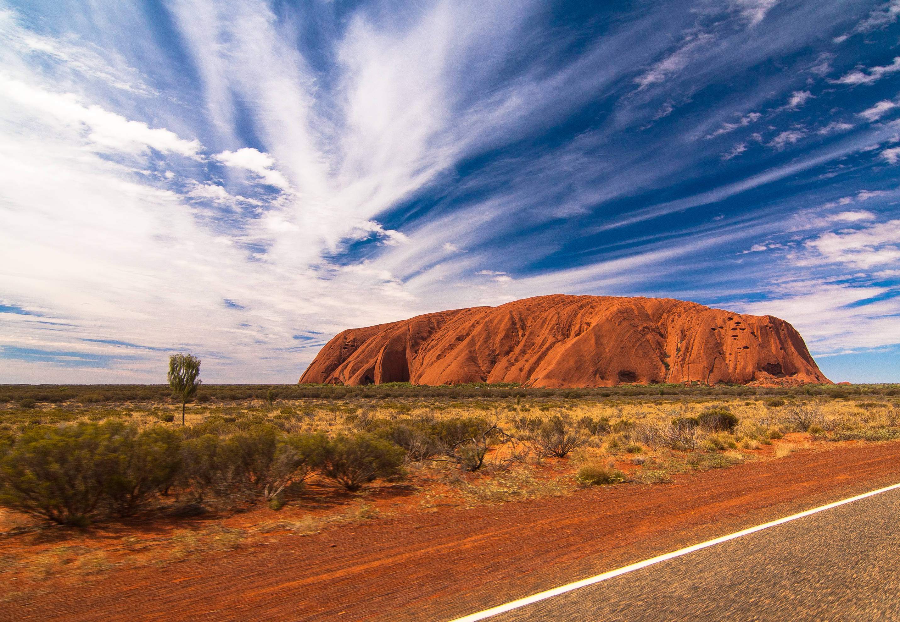 Red Centre Of Australia 壁紙 — 在乾燥的澳洲內陸，一片巨大的紅色岩層在動態的藍天白雲下雄偉地升起。