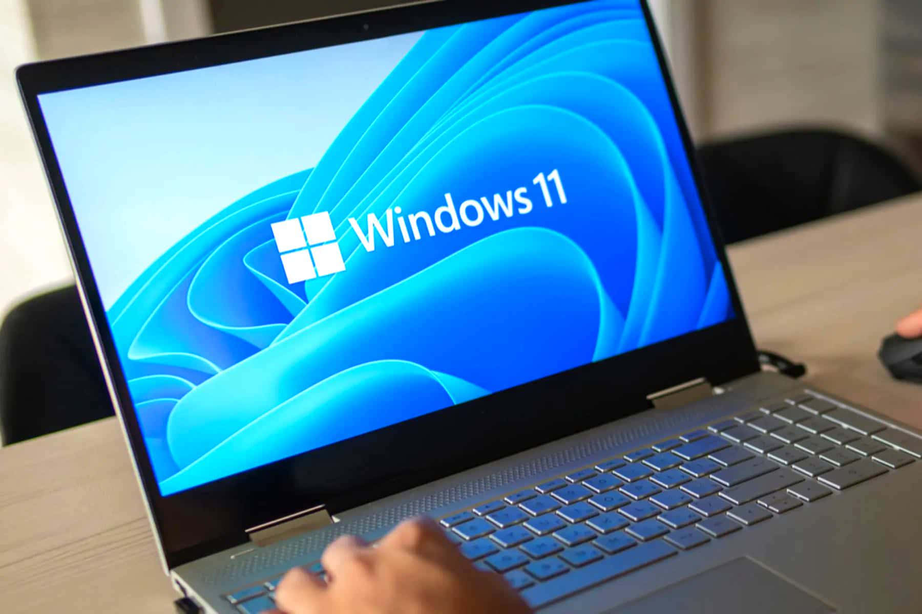 在顯示Windows 11啟動畫面的筆記型電腦上打字的手