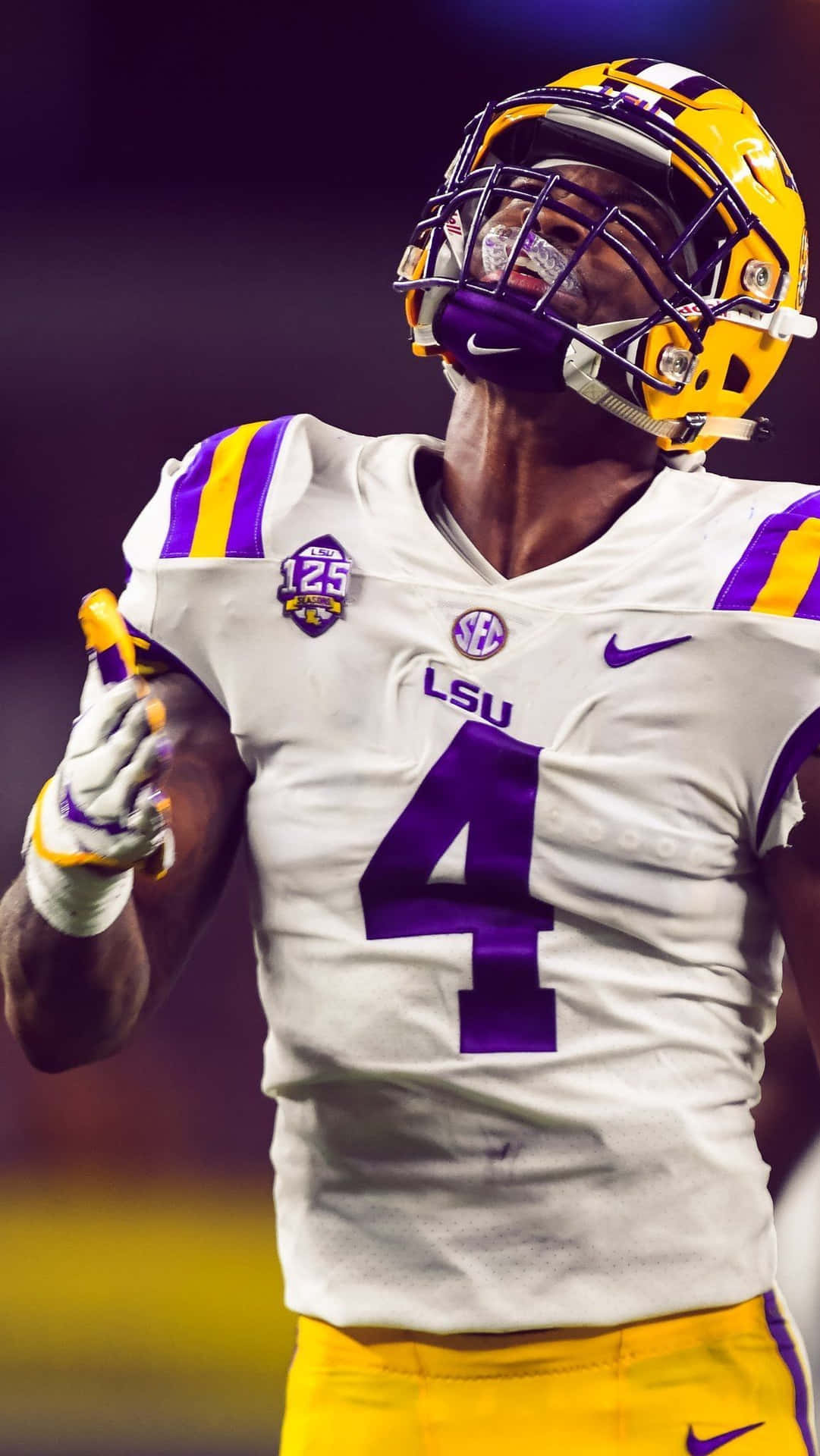 LSU 足球員在球場燈光下身穿白色和紫色制服慶祝。