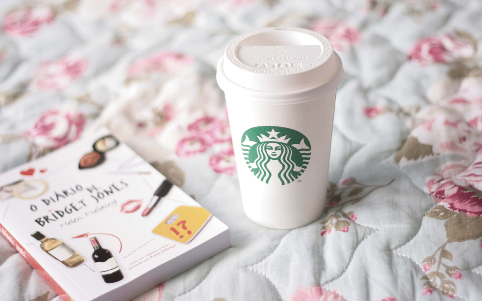 Starbucks咖啡杯同Bridget Jones書喺花卉圖案絎縫床罩上。