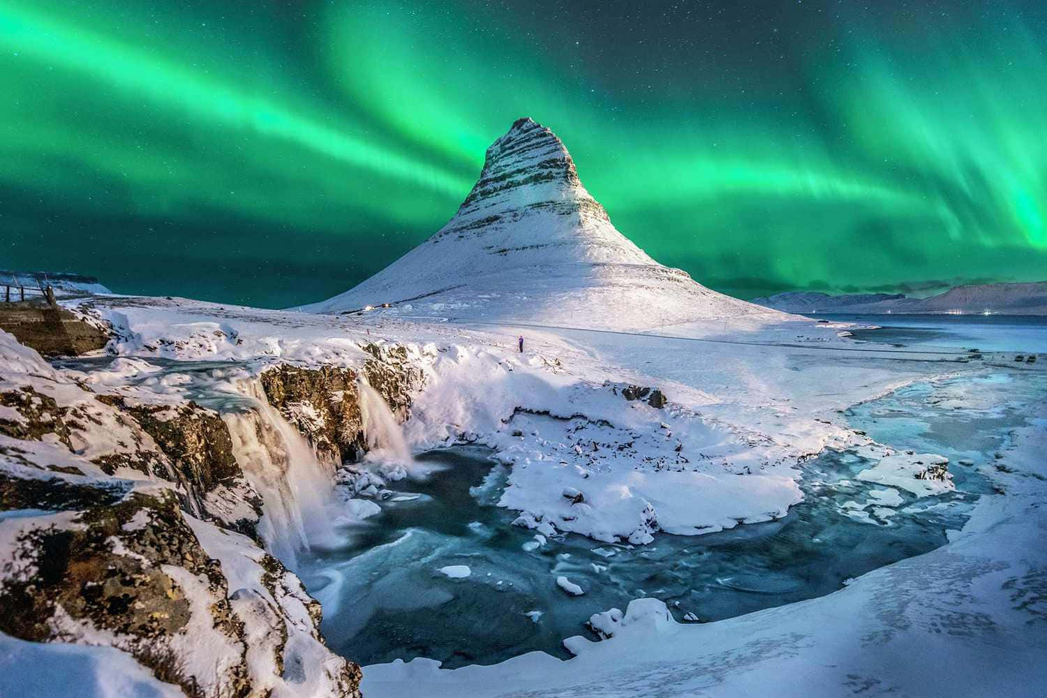 aurora borealis 桌布 壁紙 — 在充滿活力的綠色北極光下，一座白雪覆蓋的山脈，冰凍的瀑布流經冰封的景觀。