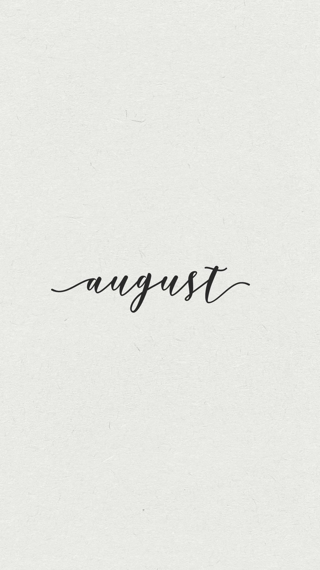 「august」一詞以黑色草書寫在帶紋理的白色紙上。