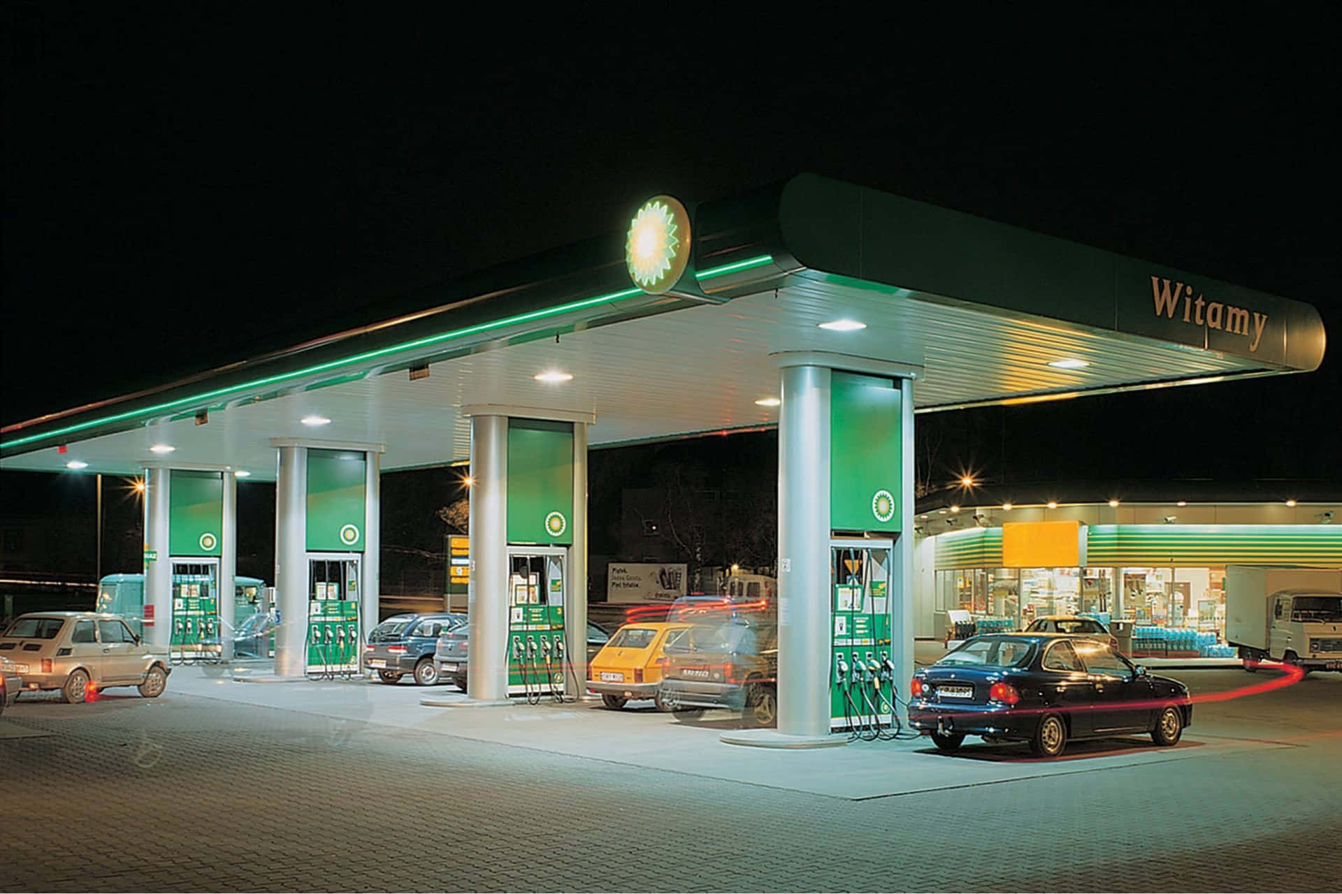 加油站夜景，汽車在明亮燈光下加油。