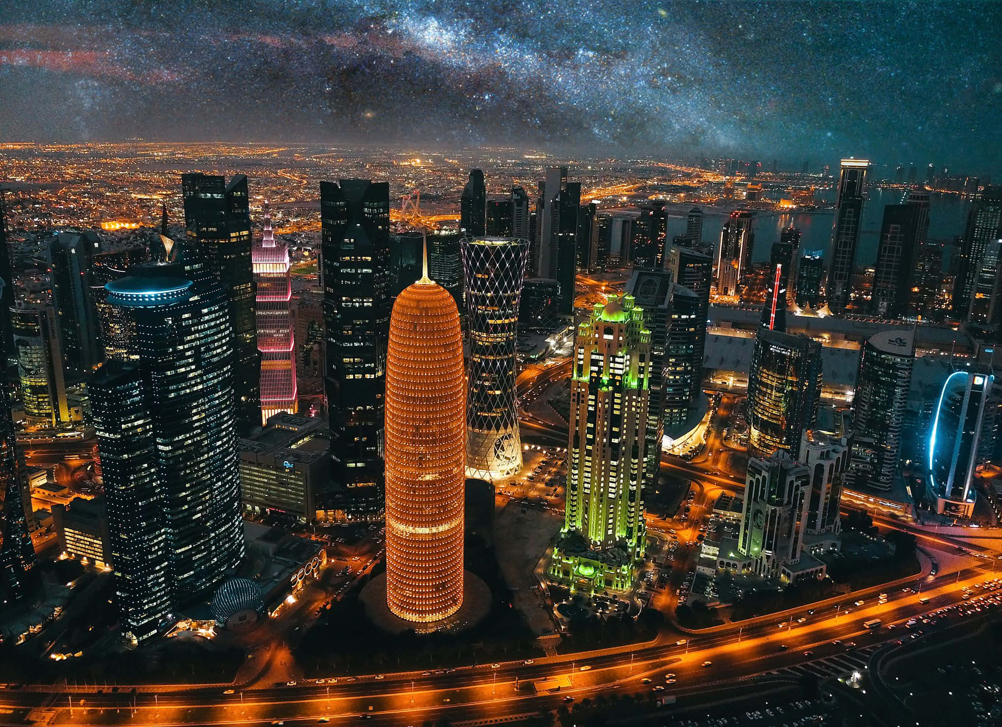 Qatar 桌布 壁紙 — 在可見銀河系的充滿活力的星空下，未來主義摩天大樓的耀眼夜景。