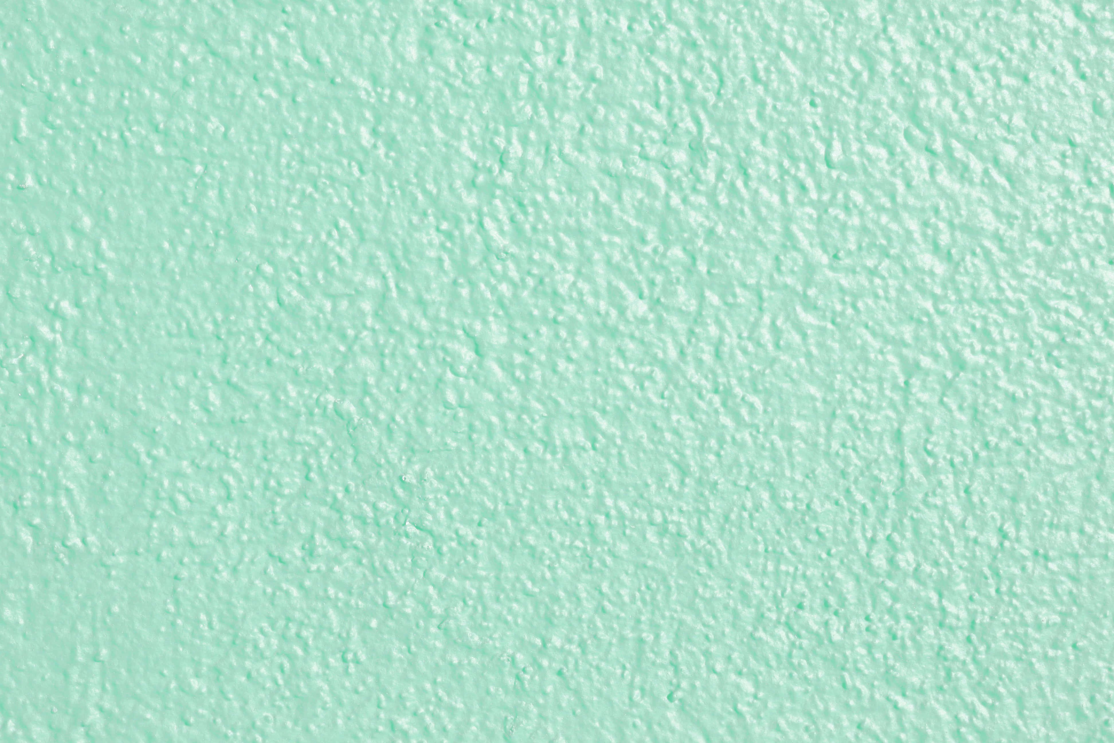 Seafoam Green 桌布 壁紙 — 在均勻光線下，平滑薄荷綠牆壁帶有細微紋理飾面的特寫。