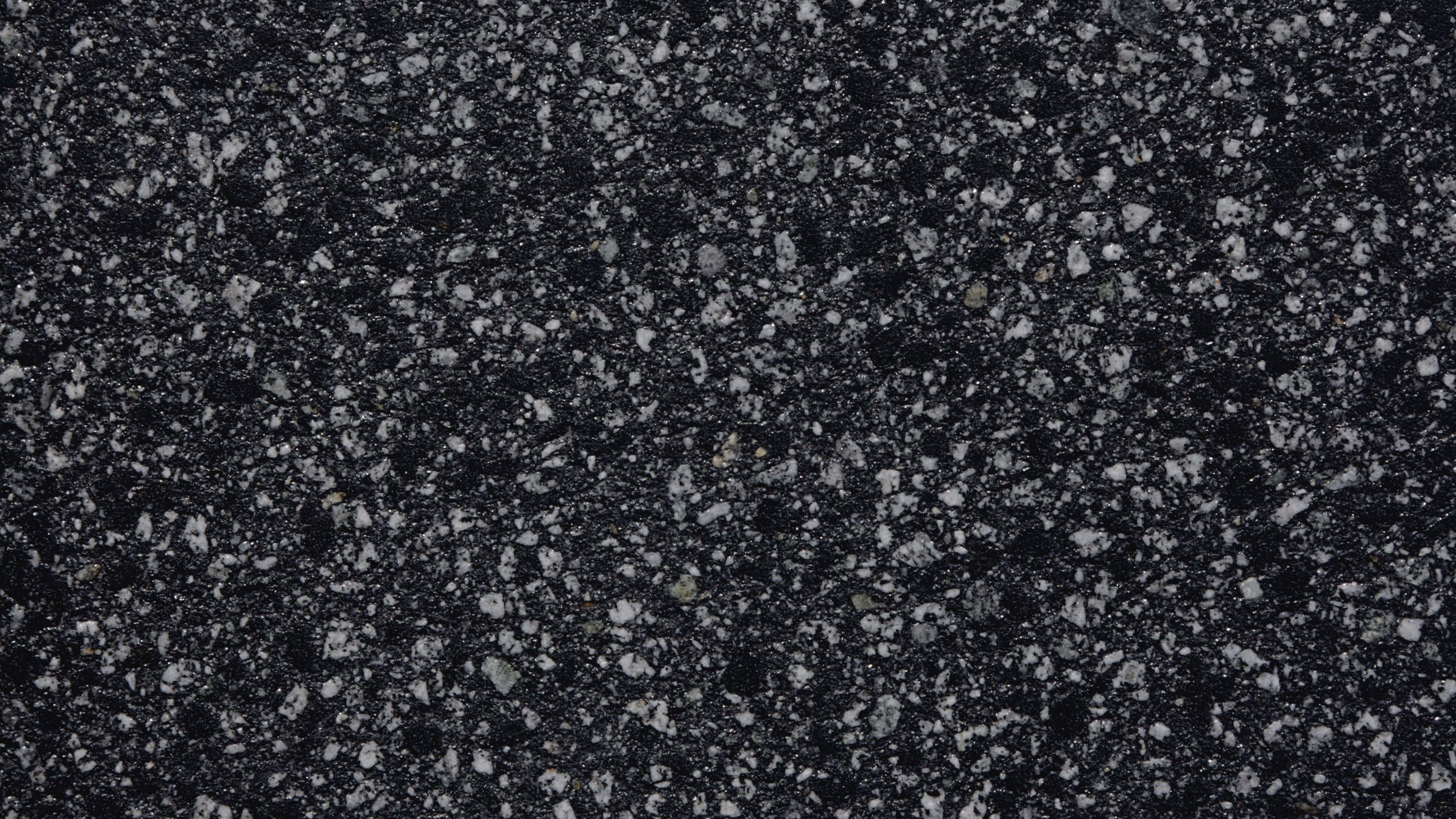 Black And White Marble 桌布 壁紙 — 在均勻光線下，深色瀝青路面帶有灰色和白色礫石顆粒的特寫。